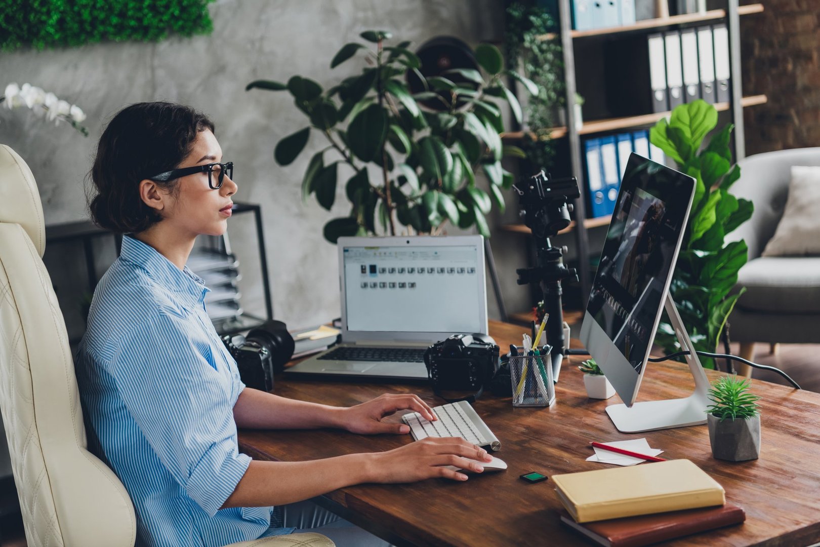 Photo of good mood happy lady photographer dressed shirt choosing portraits modern device indoors workstation workshop.