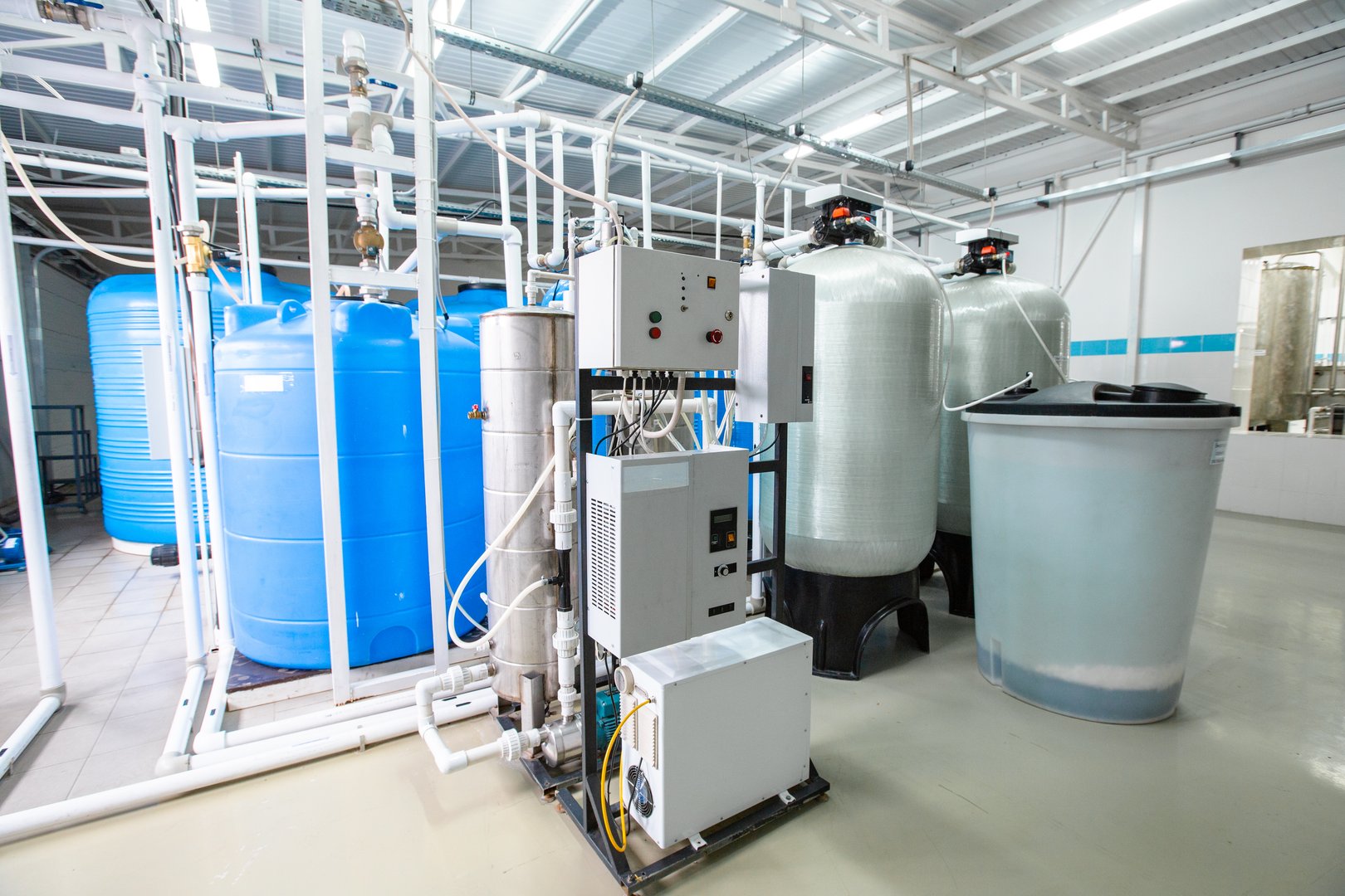 A clean and organized industrial water treatment facility showcasing large blue storage tanks and silver filtration systems essential for water purification processes.