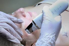 Person receiving a facial treatment with a handheld device, wearing gloves. Close-up of face and device use.