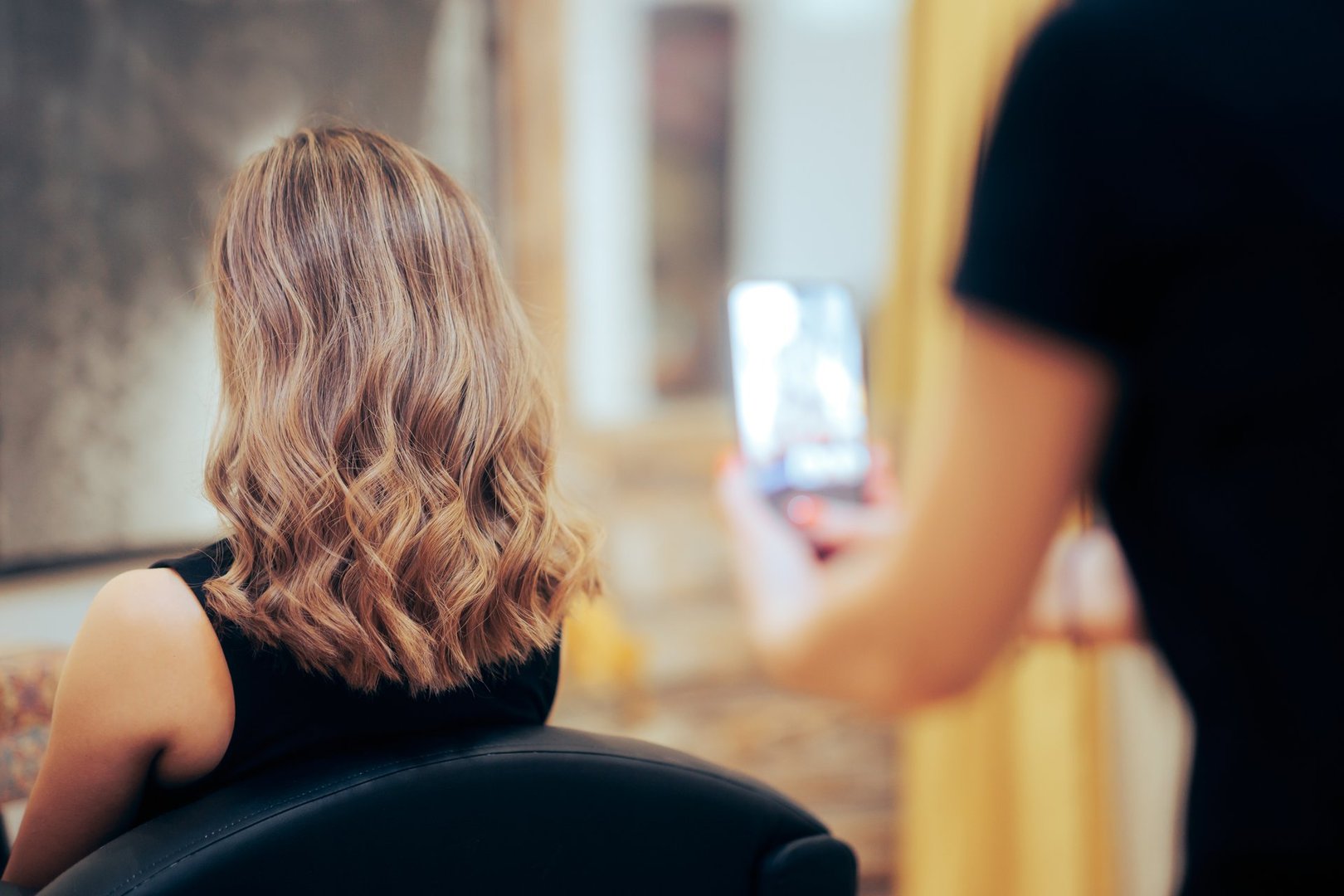 Proud hairstylist taking smartphone photos of her work