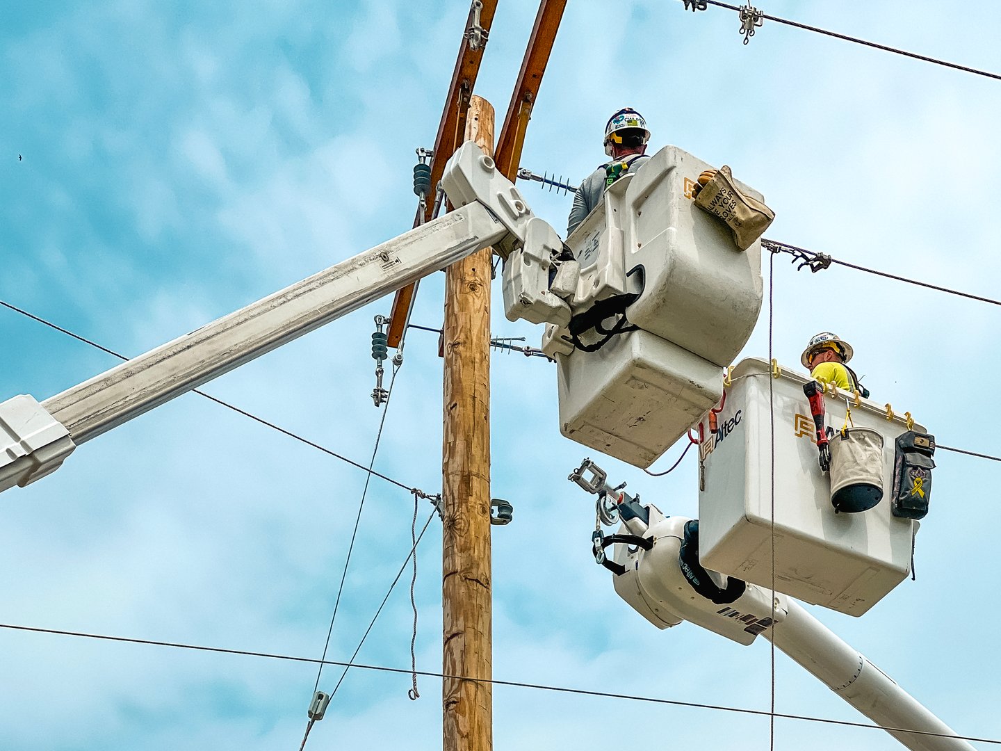 Springfield, Illinois, USA : May 9, 2024 Lineman crews work on power lines high in the sky. An elevated hydraulic bucket lifts the workers up to the power line.