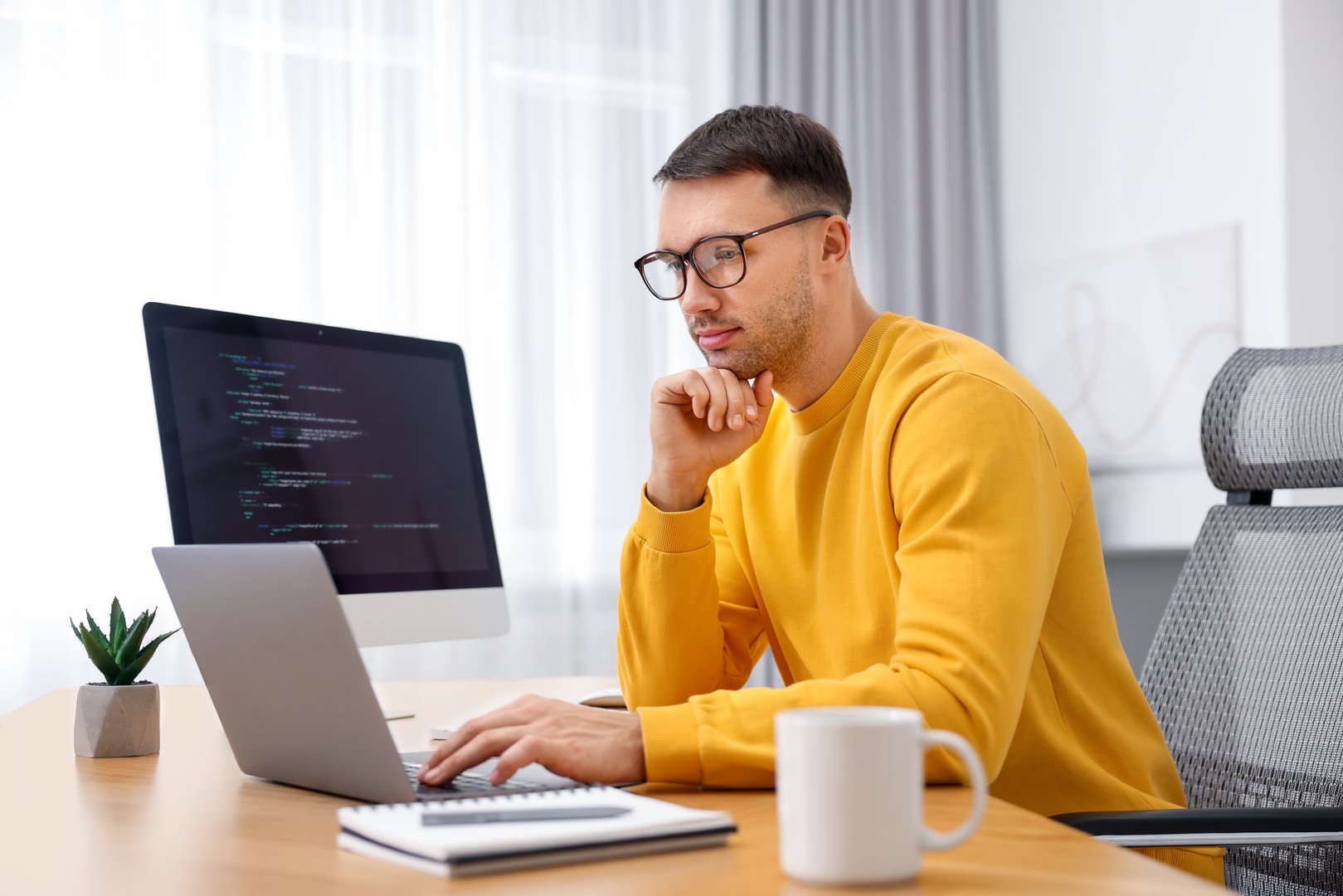 Programmer working on laptop at wooden desk indoors