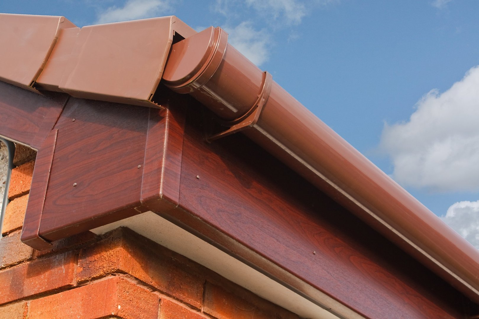 close up of Brown wood effect PVCu or plastic soffit, fascia and guttering on modern new build residential property