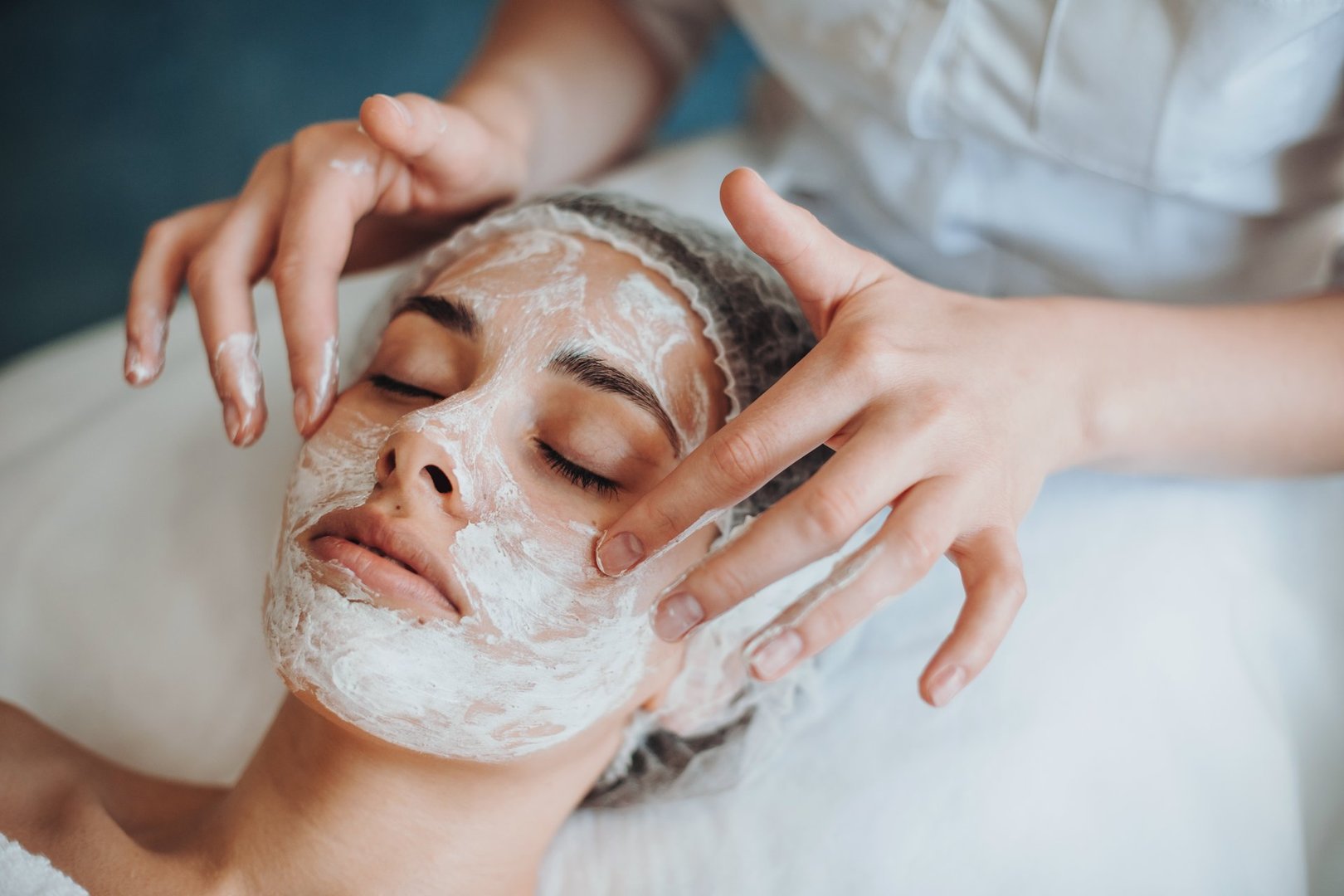 Closeup portrait of cosmetologist's hands applying mask on client's face in spa salon. Natural beauty. Facial skincare. Rejuvenation treatment.