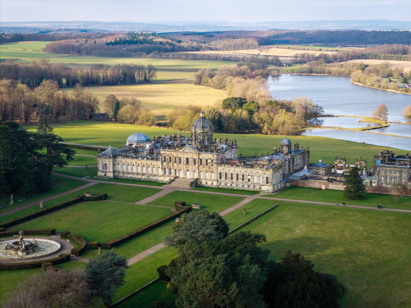 Castle Howard, York, UK - February 2, 2025. Aerial landscape panorama of Castle Howard stately home and gardens in the Howardian Hills on a beautiful sunny day with the Great Lake in the distance