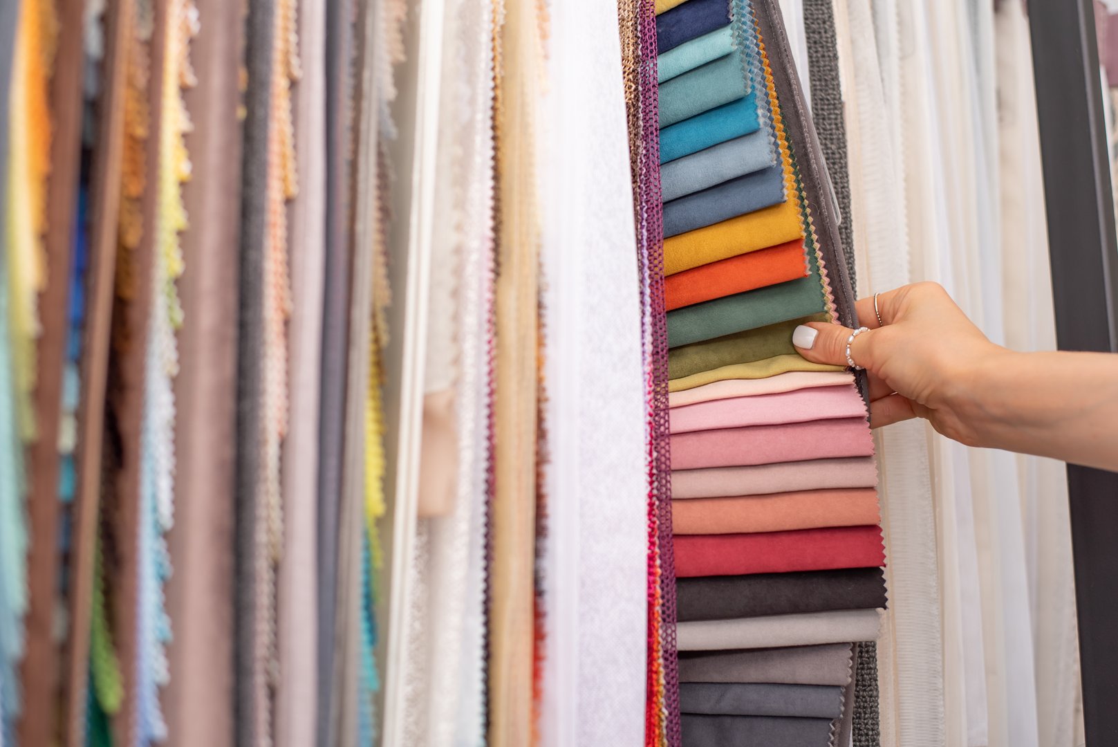 The girl is holding samples of colorful fabric for curtains and home textiles. Samples of textiles for curtains.