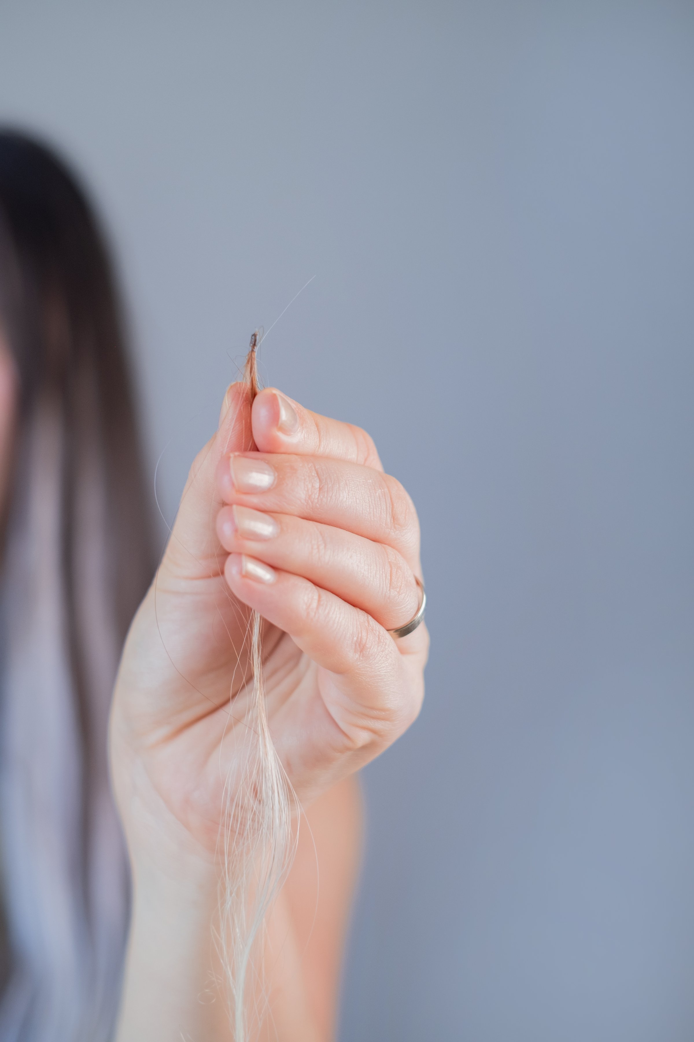 Hairdresser demonstrating invisible hair extension technique professional hairstyling in modern beauty salon