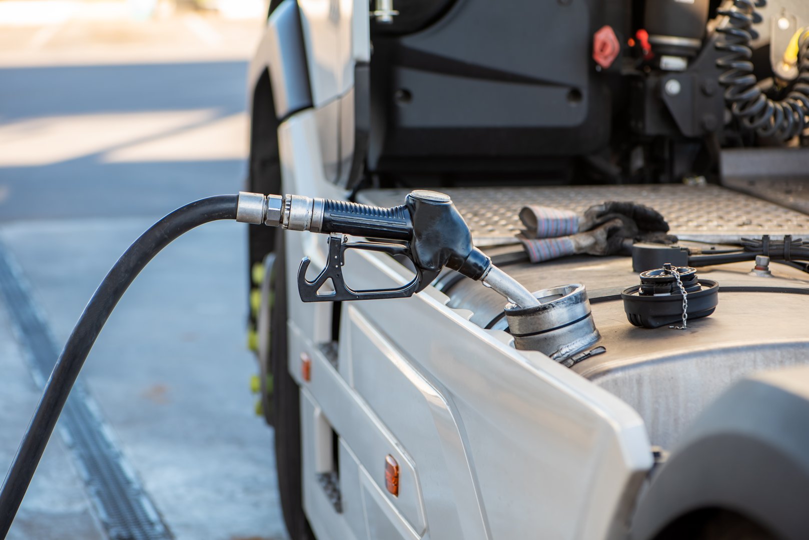 Diesel nozzle from a gas station connected to the fuel tank opening of a truck.