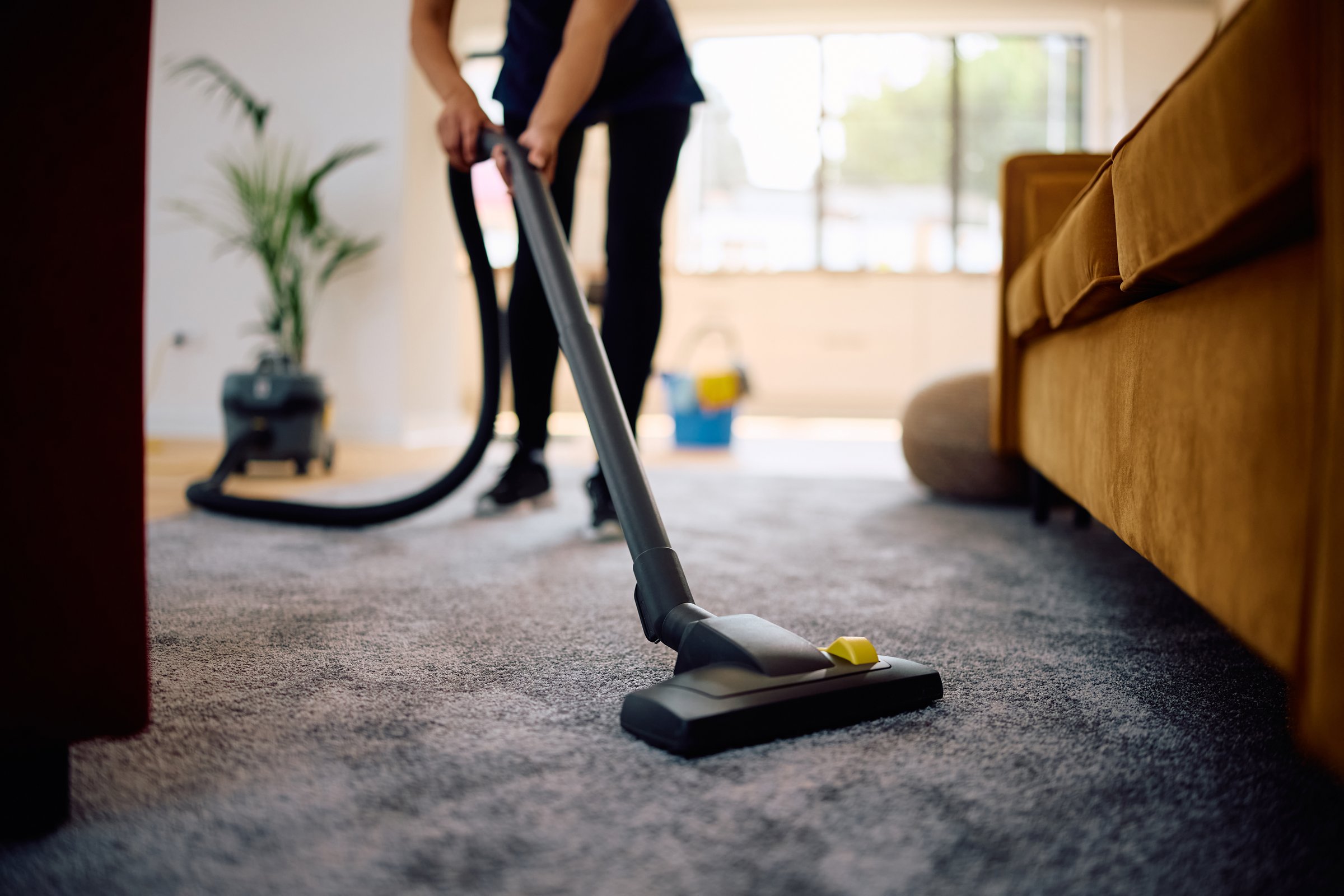 Close up of woman vacuuming while working professional cleaner.