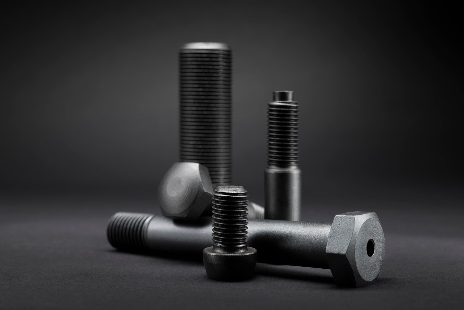 Variety of large black steel screws on black background.