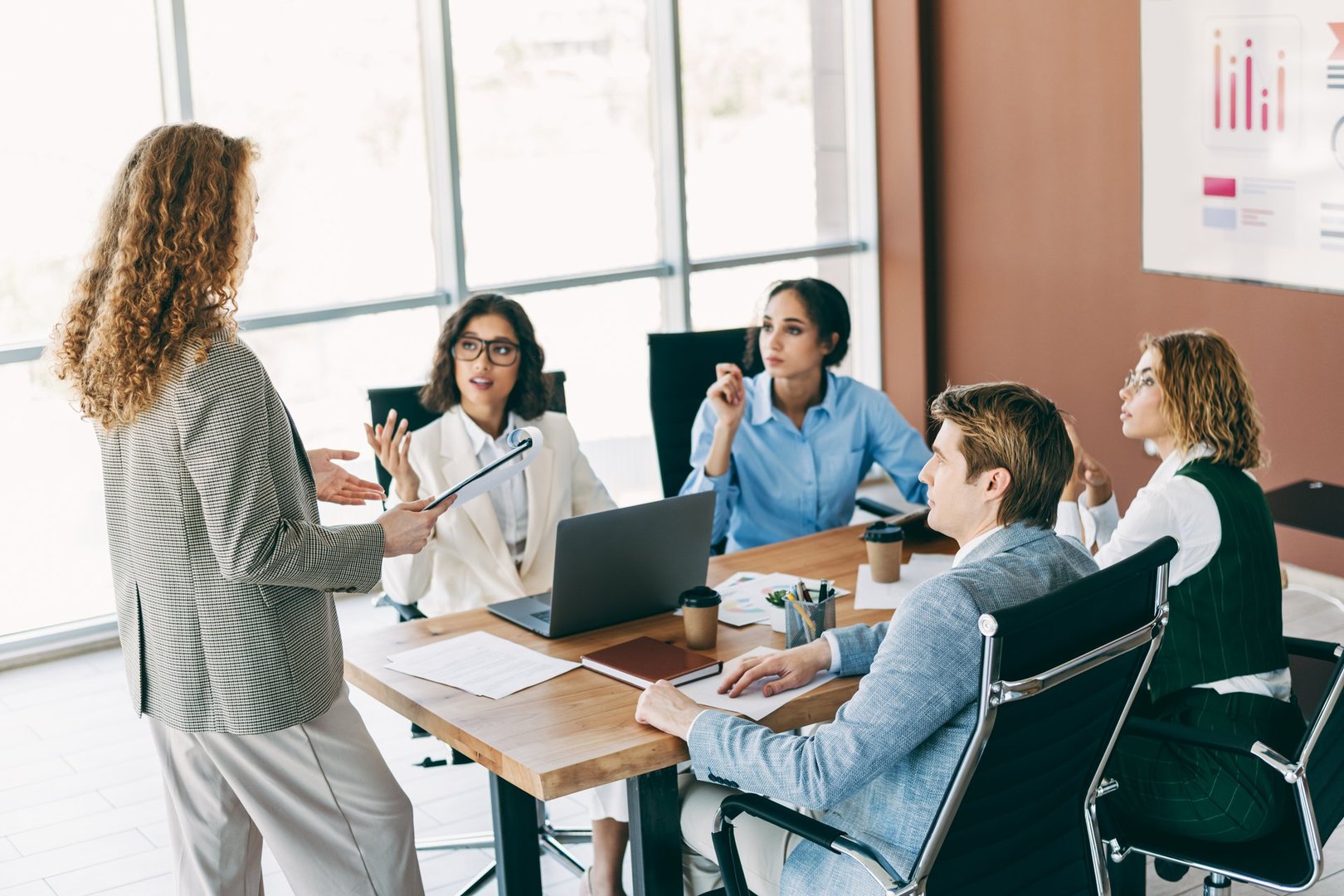 Business professionals in a modern office engaging in a teamwork-focused meeting to discuss strategies and corporate goals. Various roles and collaboration dynamics are illustrated within a workplace environment.