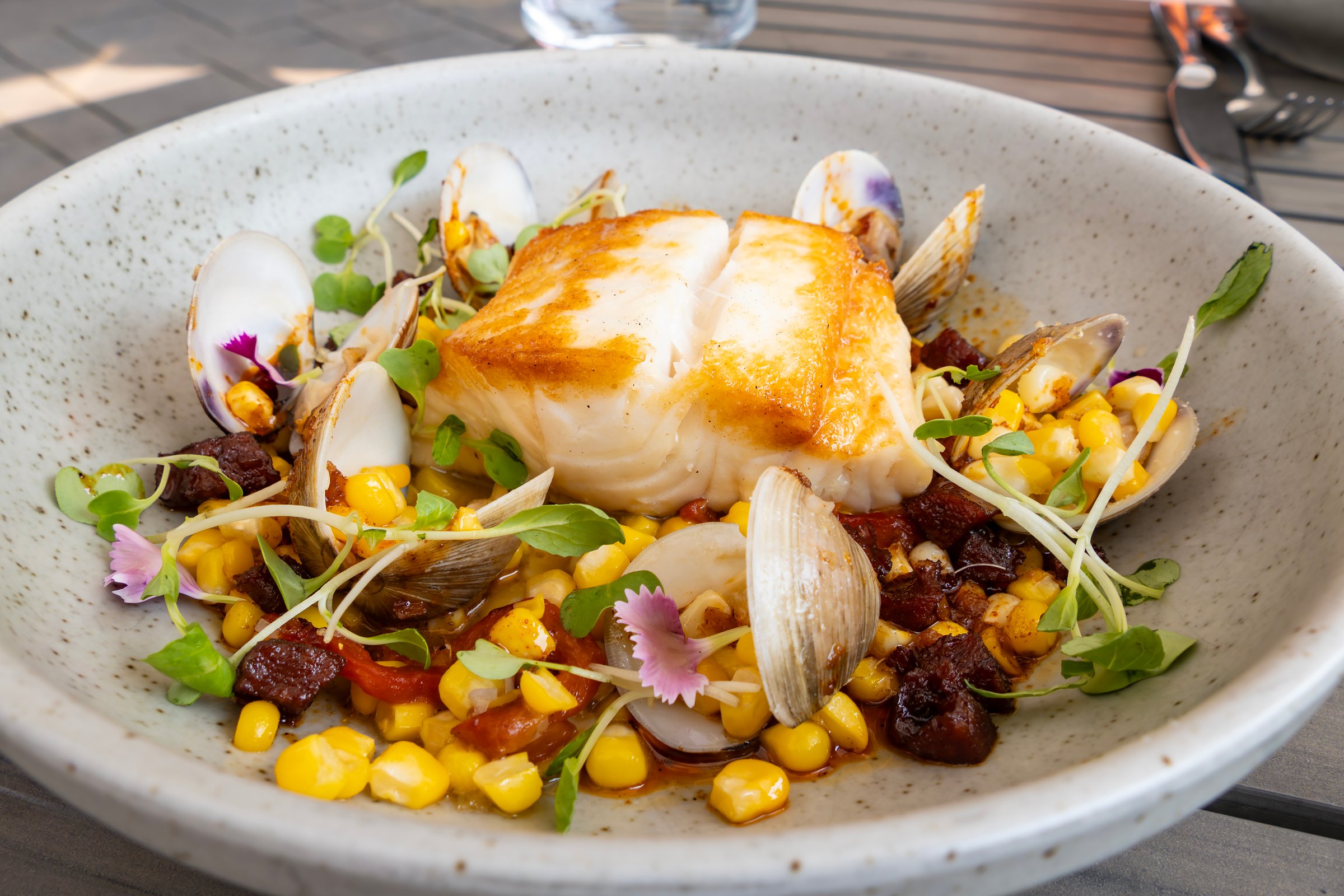 A Colorful Dish of Cod Fish Served with Clams and Colorful Vegetables