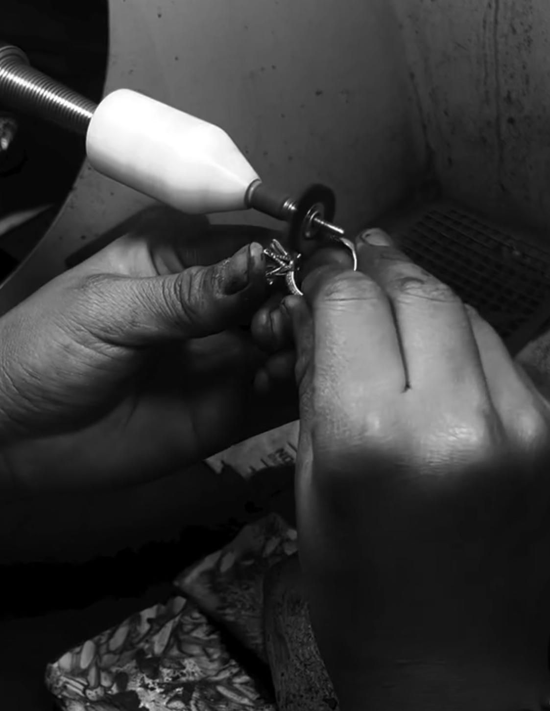 A person polishing a ring using a rotary tool, focusing on craftsmanship and detailing.
