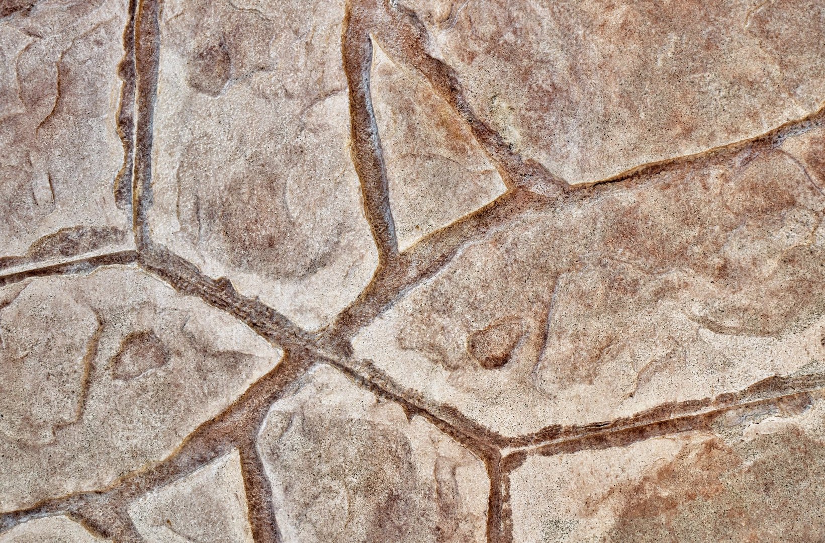 Stamped concrete mosaic patterns, earth tone colors and textures from directly above. A procedure of stamping cement to resemble tile, wood or other materials.