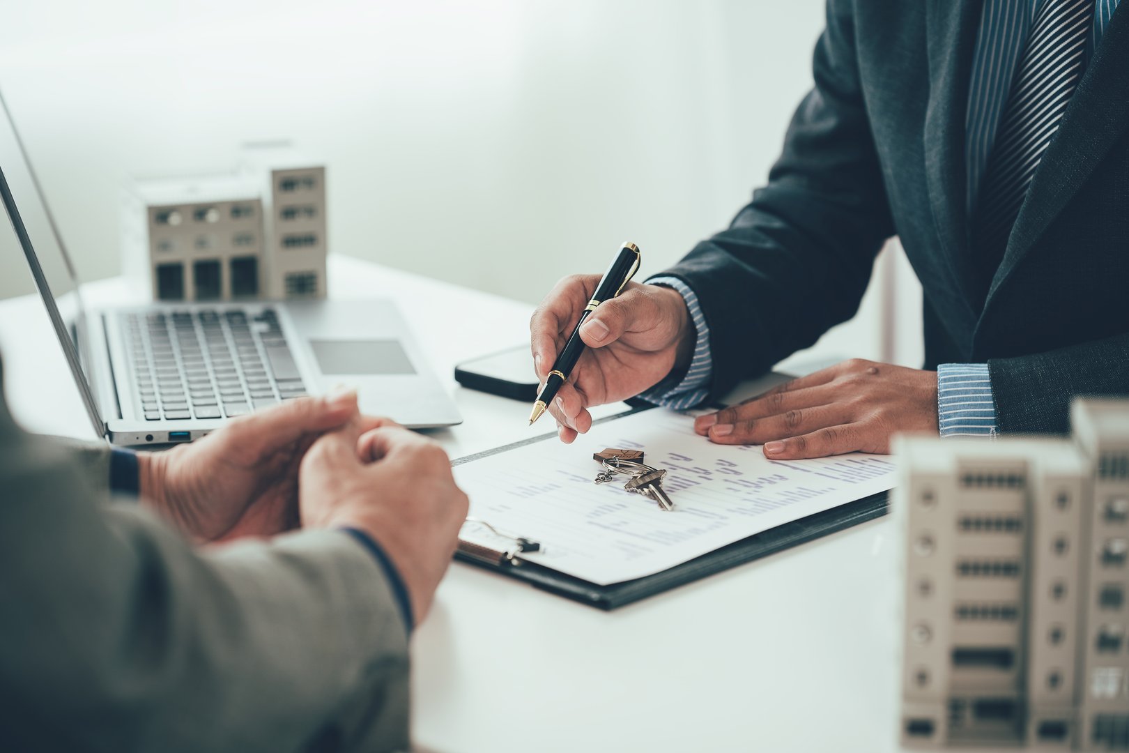 A real estate salesperson introduces a customer to a model home project and hands the keys to the customer. New home buyer approved for home loan, close-up photo