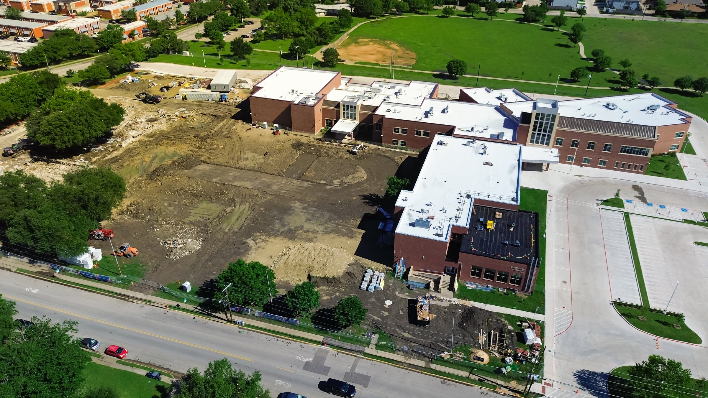 Site preparation, paving, utilities storm drainage system installation at elementary school renovation classroom building construction near Marcus Park in North Dallas, heavy machine working. USA