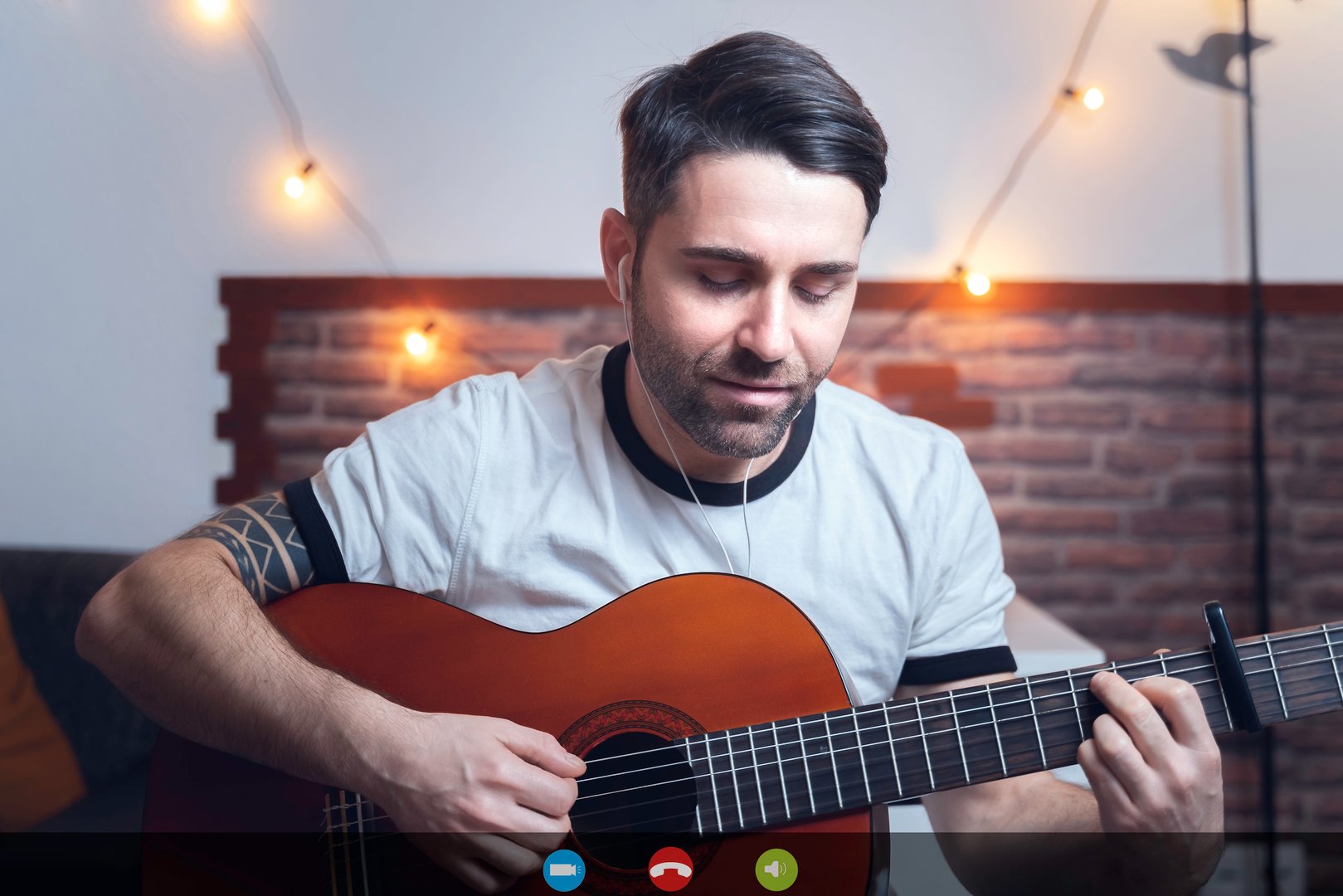 Photo of a screen, during a video call, of a young boy, playing guitar.