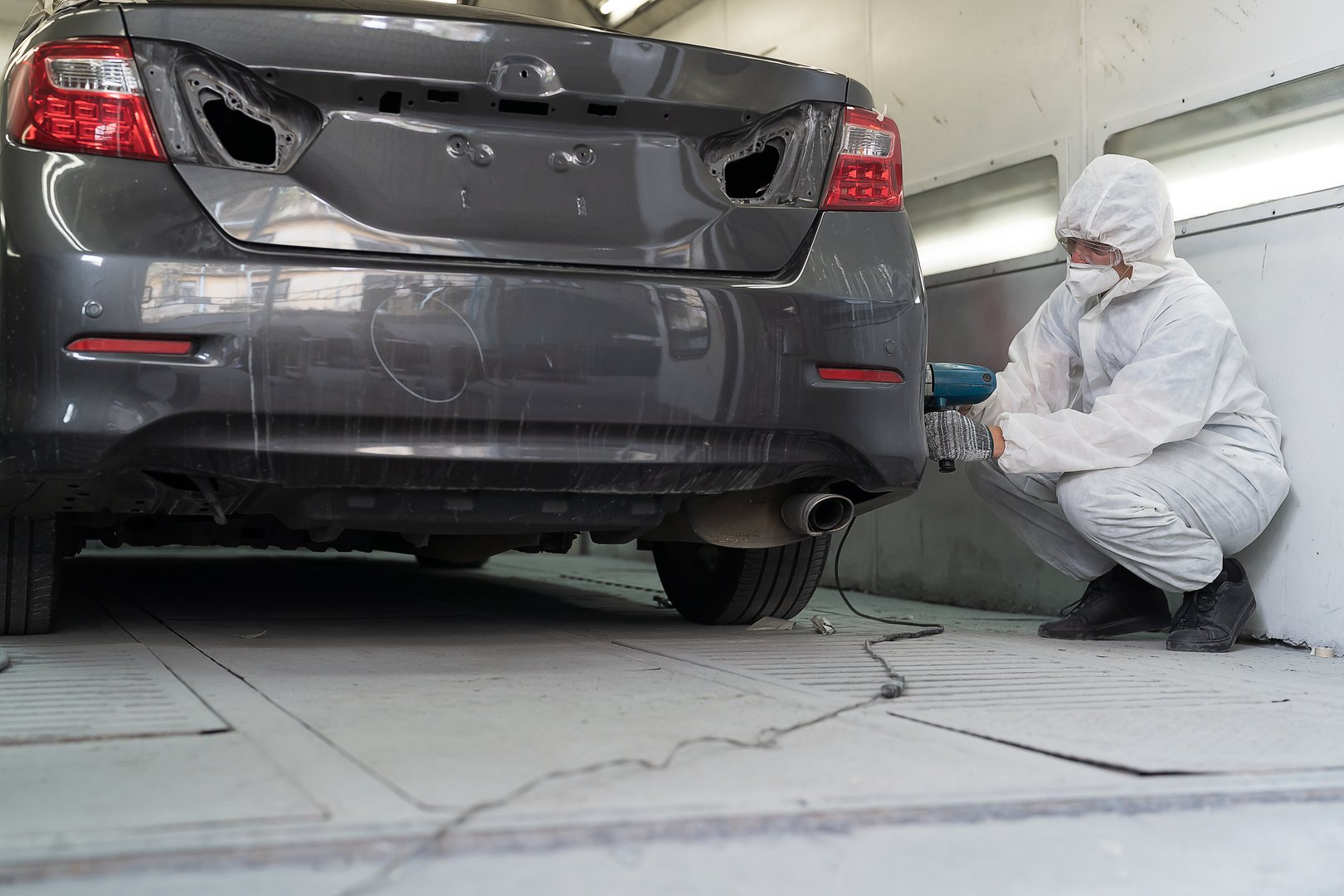 Vehicle polishing and detailing service. Worker using polisher machine for polishing at car auto service