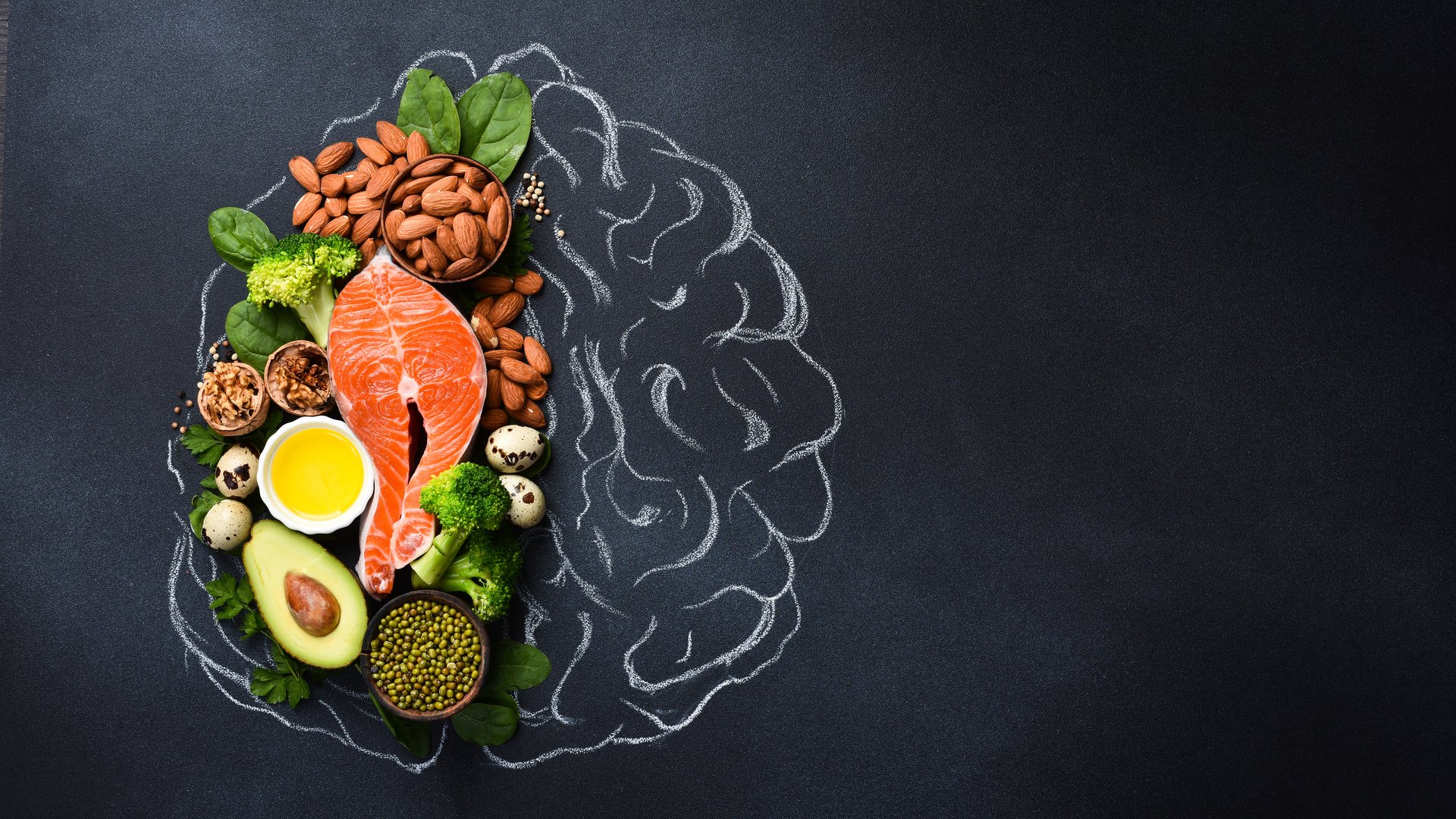 A picture of the brain drawn in chalk with various food products: fish, meat, nuts, vegetables and greens. Healthy food.