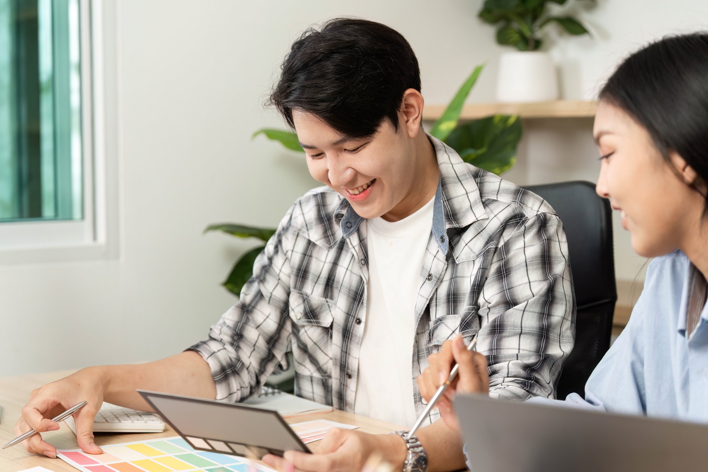 A young man and woman share insights and color schemes during a UX and UI design session, fostering creativity and teamwork.