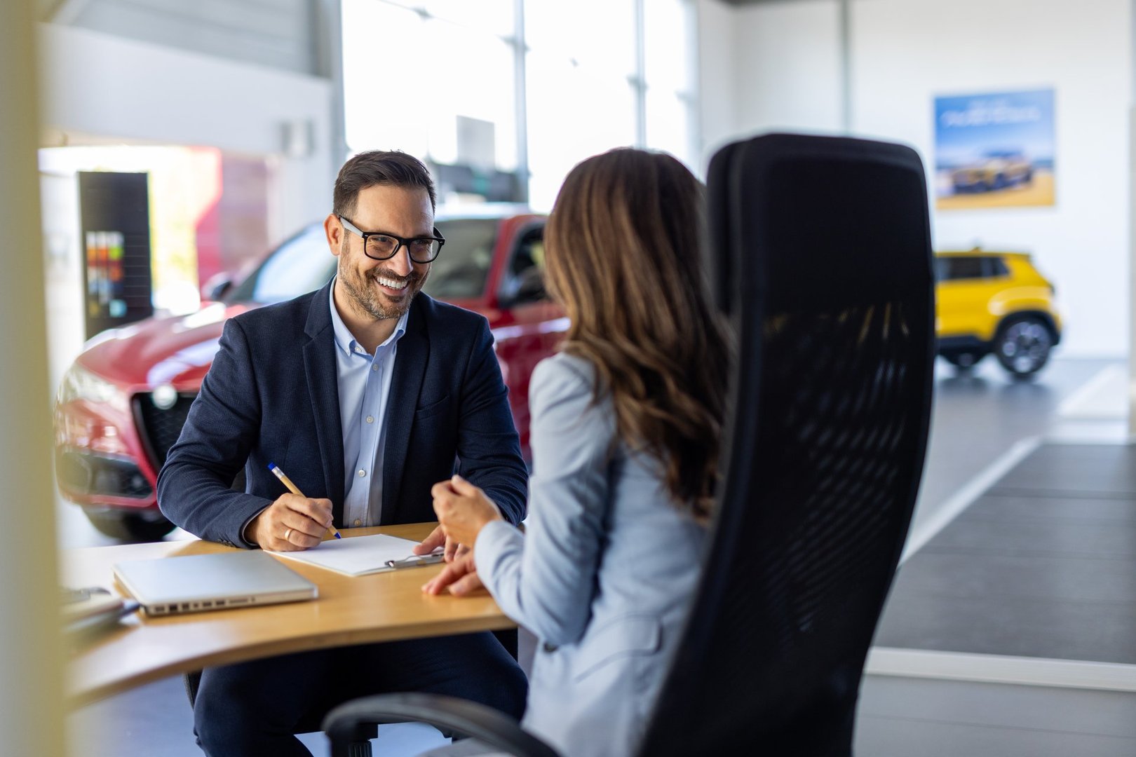 Young woman signing car insurance document or lease paper contract or agreement. Buying or selling new or used vehicle with car keys on table.