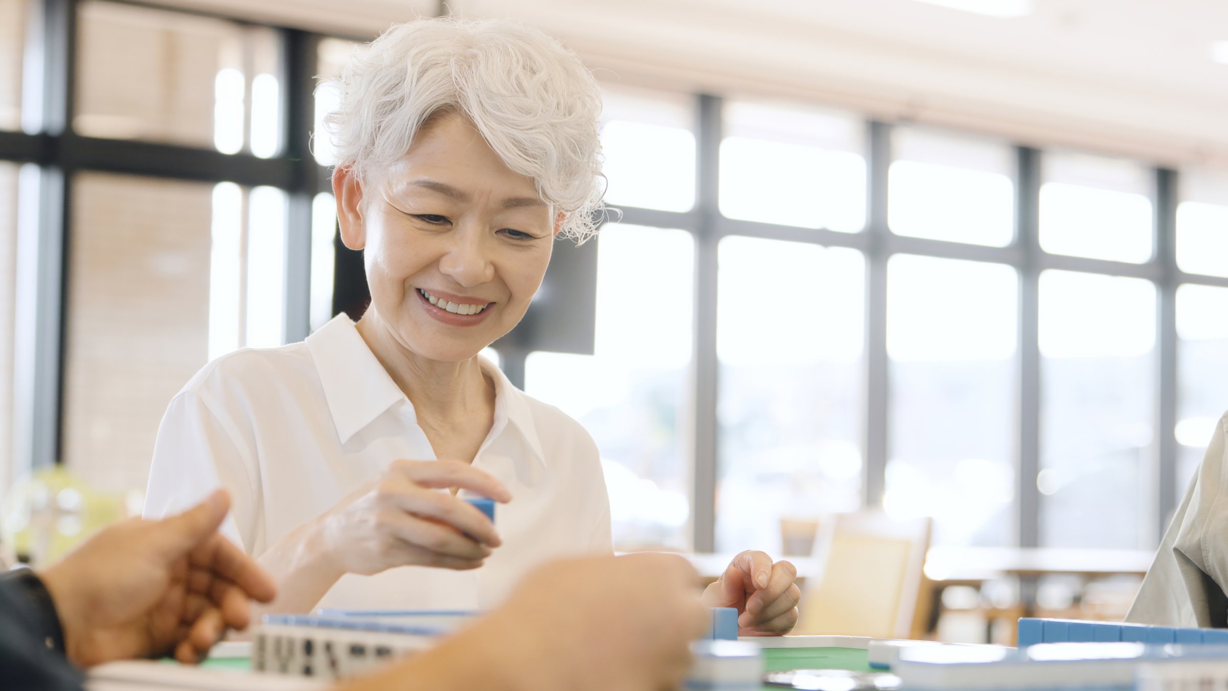 Asian elderly people playing mahjong in a care home