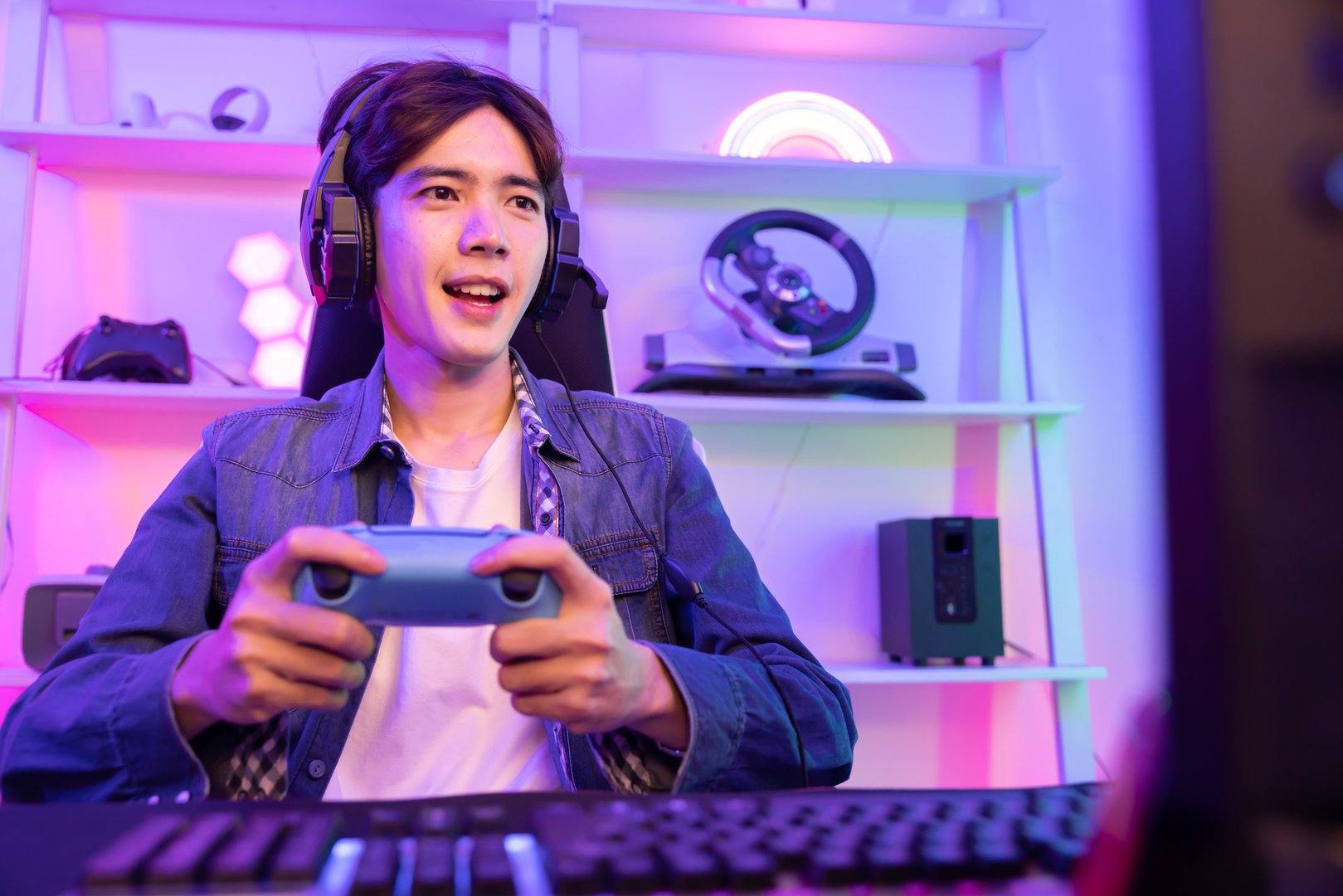 Male Gamer Playing Console Game with Game Controller in Neon Game Room
