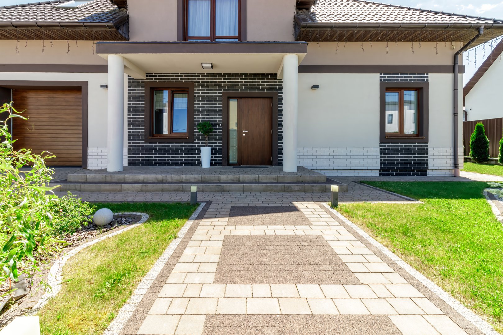A beautifully designed modern house, featuring brick details, a landscaped yard, and a welcoming entrance pathway.