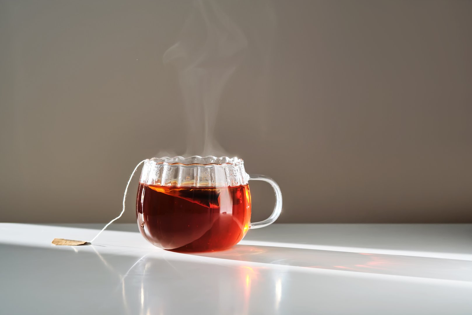 Glass mug with hot black tea on the table. High quality photo.