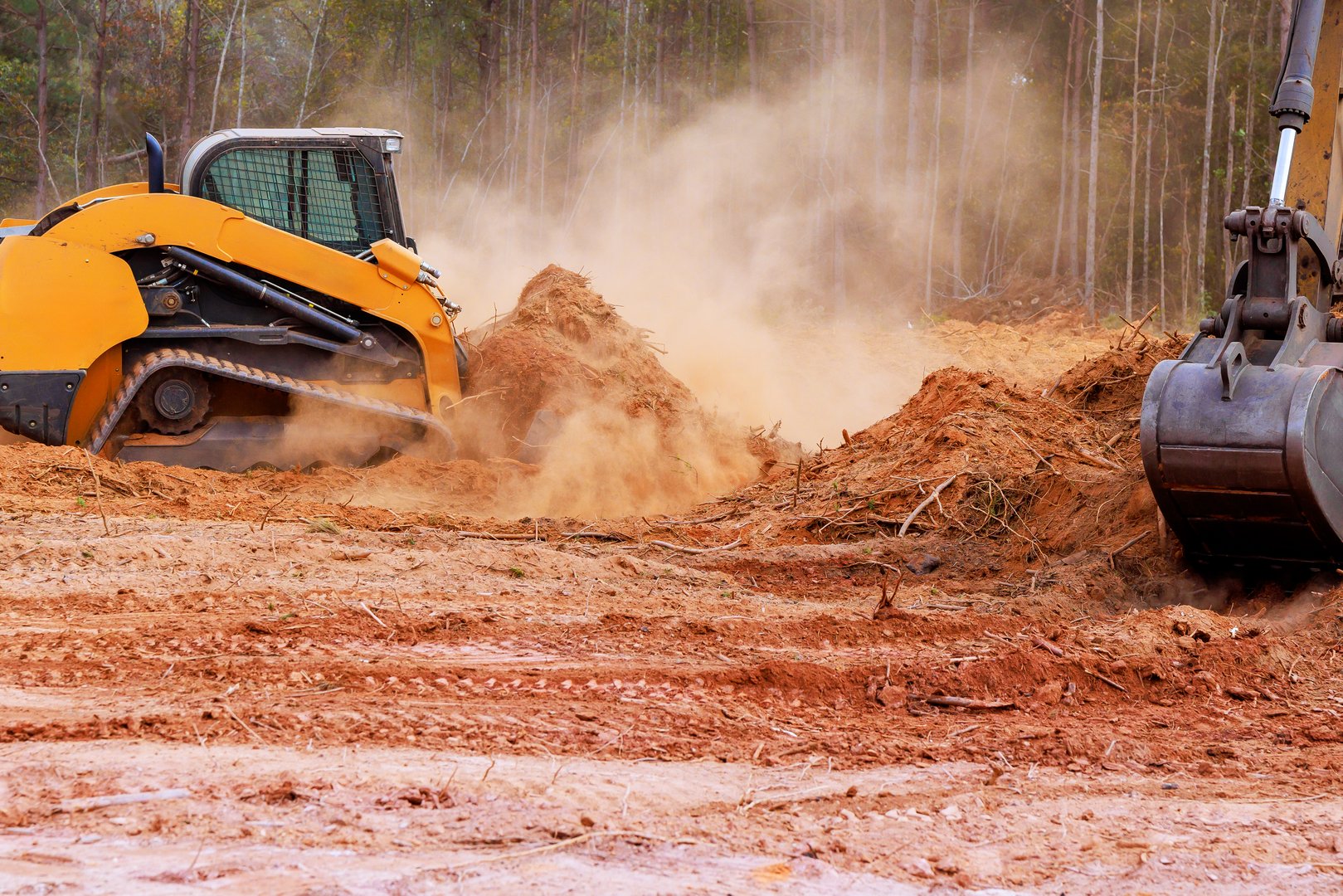 In course of earthworks, small earthmoving tractor is leveling ground during construction
