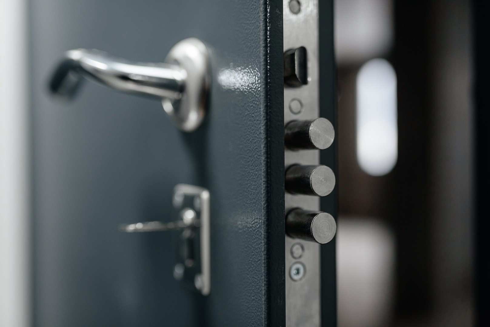 modern metal door to apartment, lock in three rods form, door slightly open, key in keyhole, coming home concept