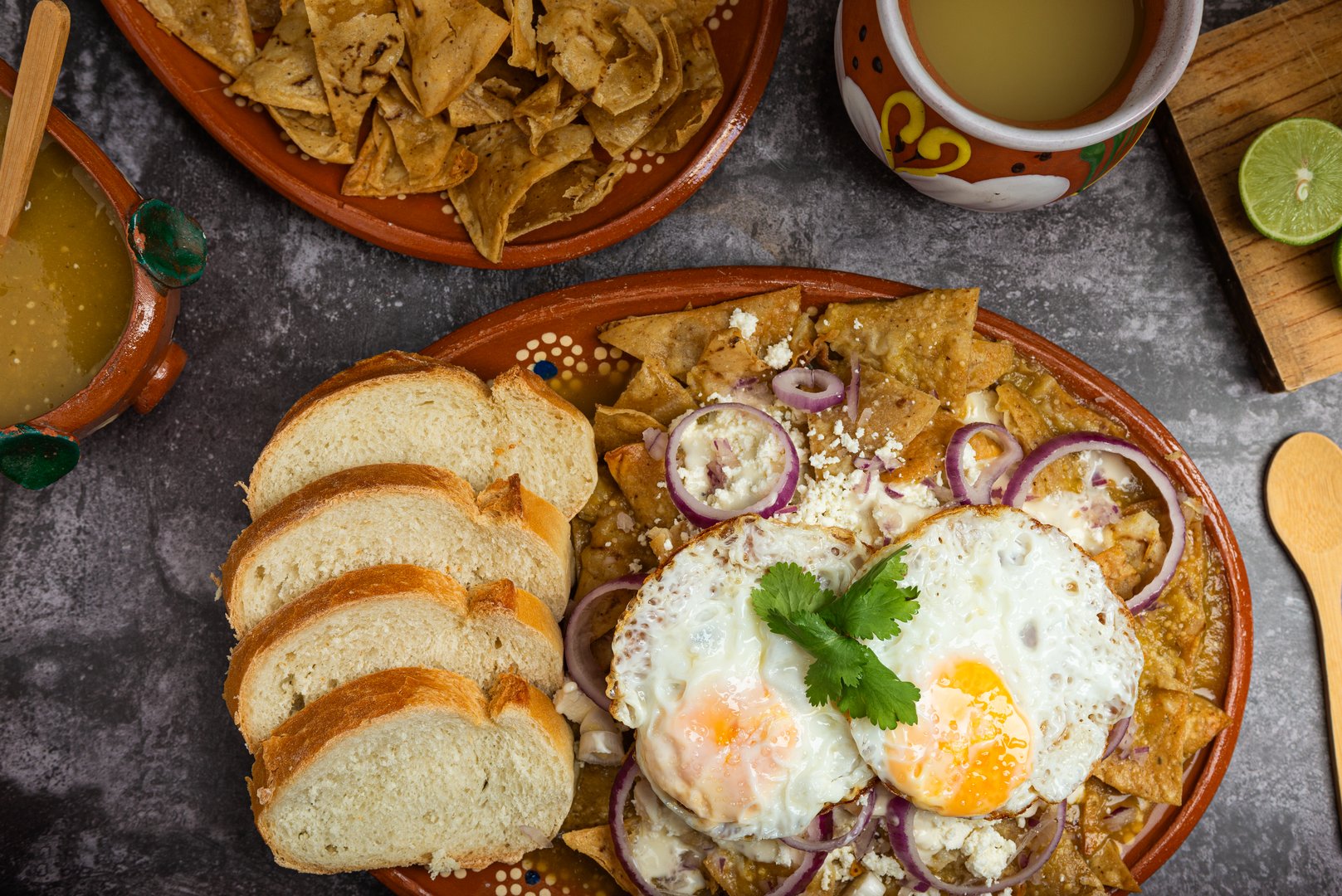 Chilaquiles, typical Mexican food, served in a clay dish with fried eggs and bread.