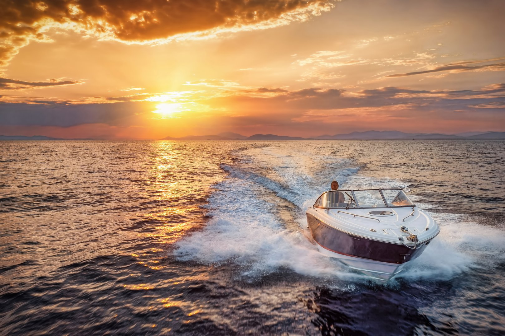 Aerial font view of a motor speedboat cruising over the ocean during golden summer sunset time