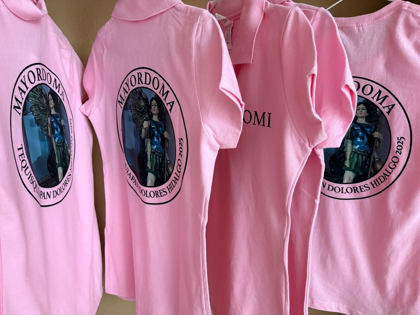 Smiling female printing workshop worker standing at facility with silkscreen printed t-shirt and showing it at the camera and promoting lgbtq equality. Print shop worker with finished product in hands