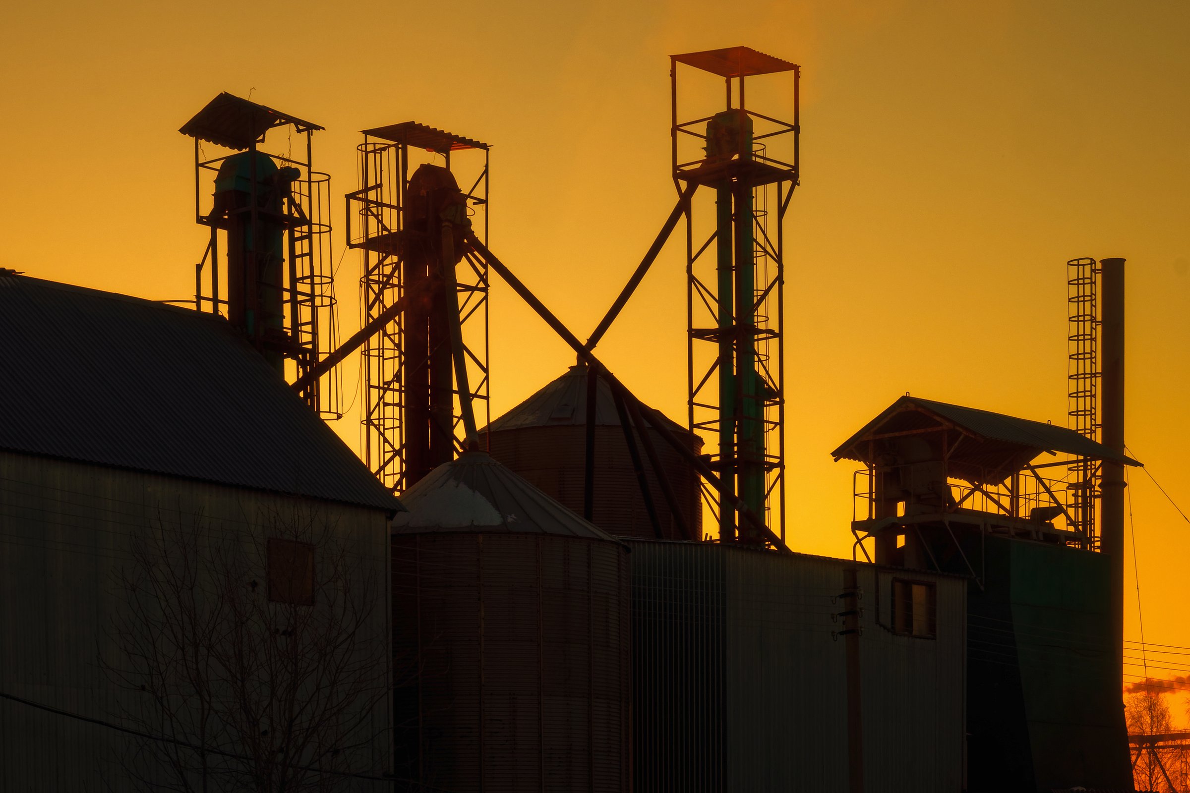 Silhouette of small factory against sky at dawn. Factory small business. Cinematic frame. Dramatic light. Industrial background.