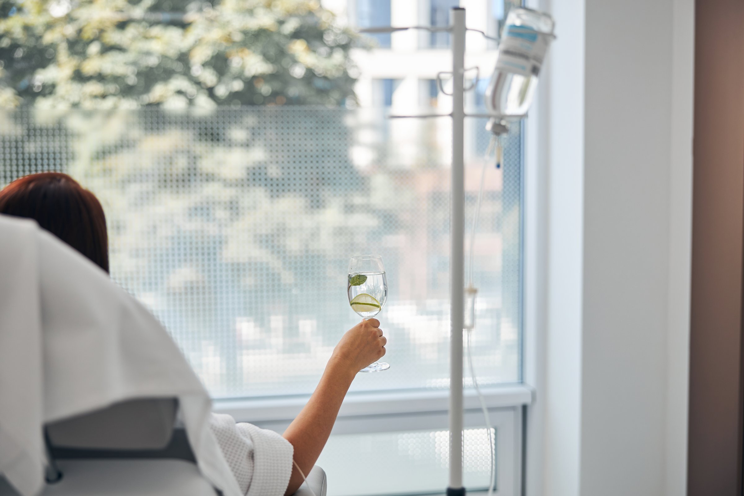 Back view of a patient sitting in a cosmetic chair during the intravenous vitamin therapy