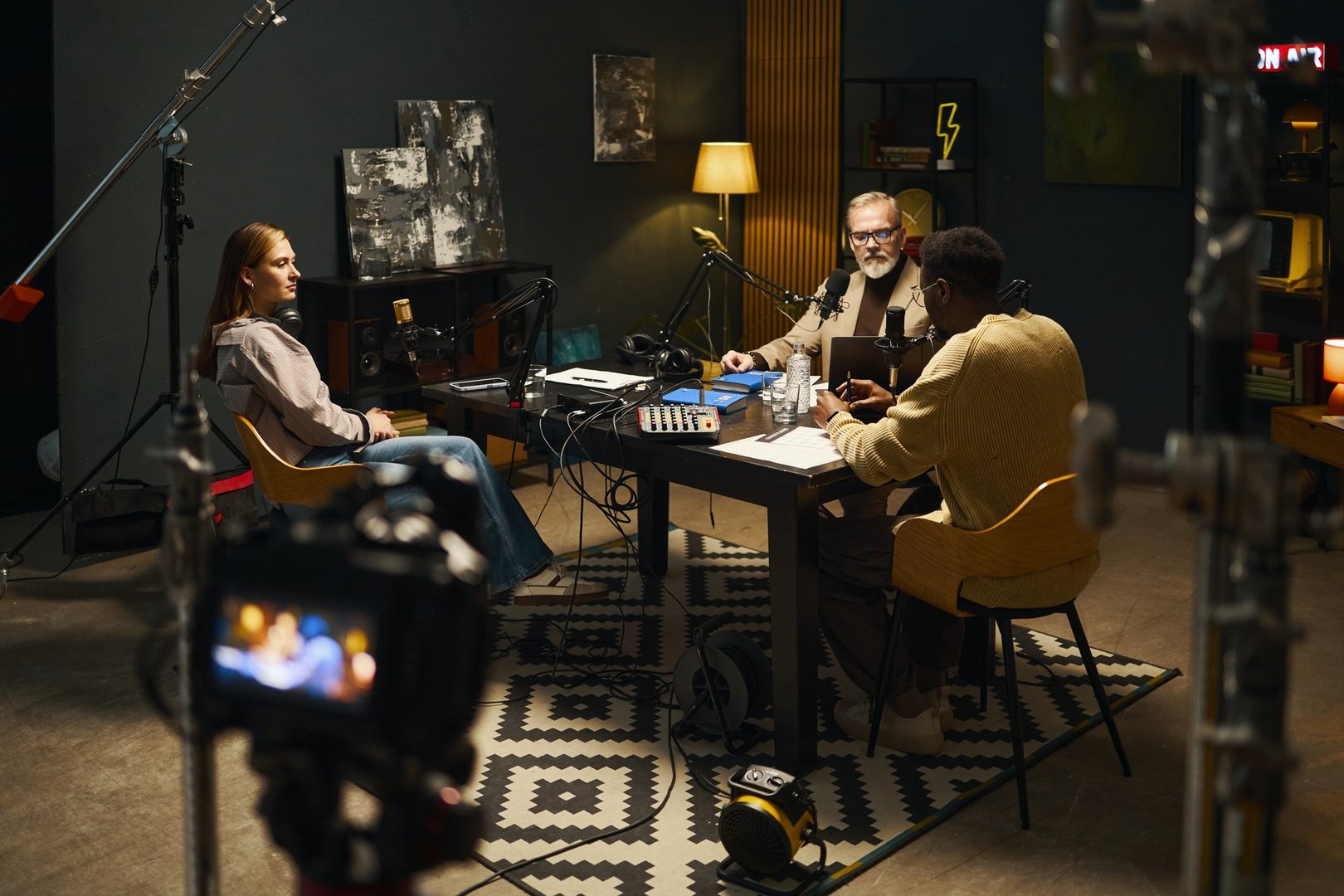 People sitting at table with microphones and talking while recording podcast in studio