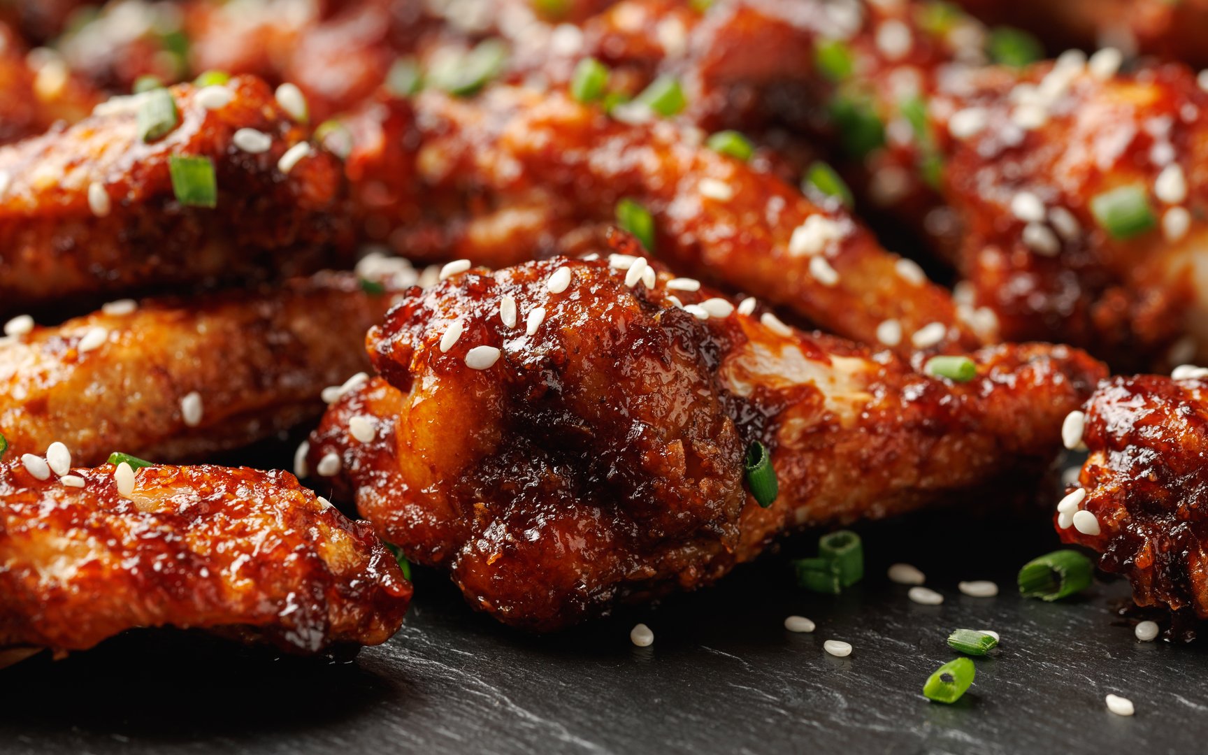 Spicy korean chicken wings with sesame seeds and chives.