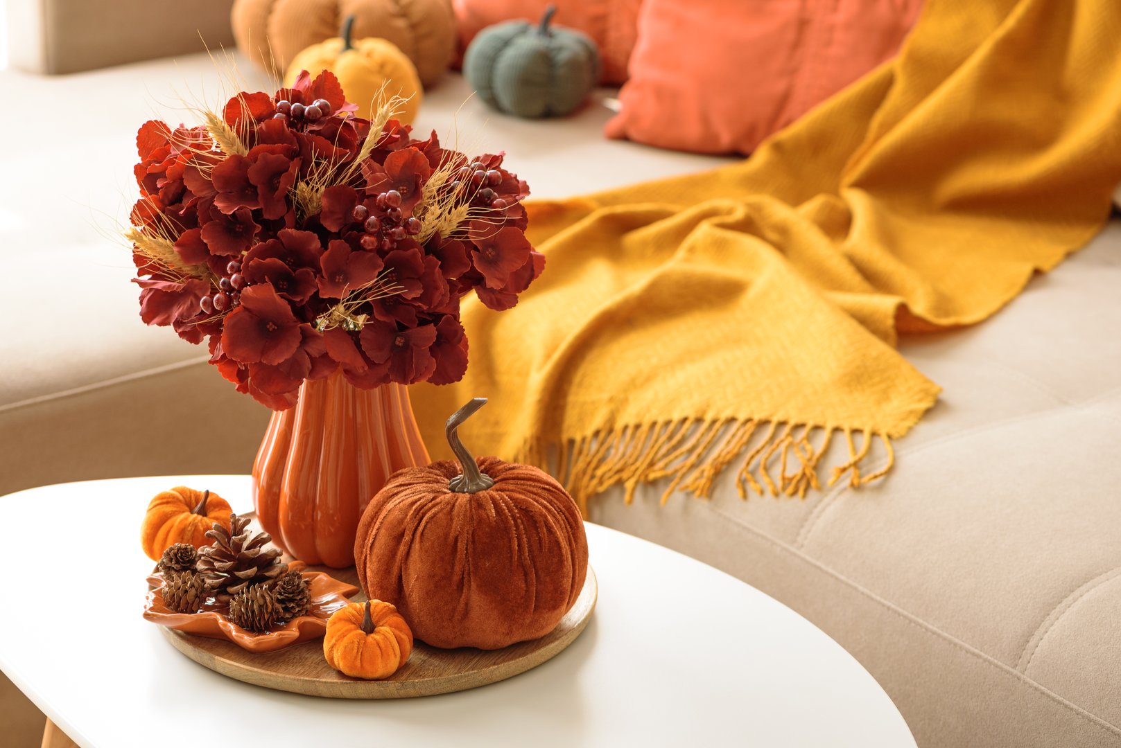 Thanksgiving living room decor with a coffee table, pumpkins and a floral arrangement.