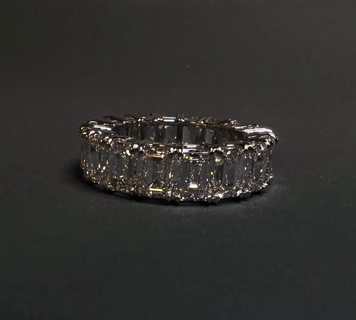 An elegant ring adorned with large, rectangular-cut diamonds set in a continuous band against a dark background.