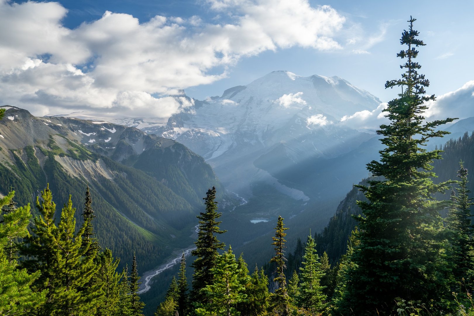 A breathtaking view of snow-capped Mount Rainier rising above lush evergreen forests in the Pacific Northwest. The majestic mountain and pristine nature create a perfect scene for outdoor adventure, hiking, and wilderness exploration. Ideal for themes of travel, nature, and environmental beauty.