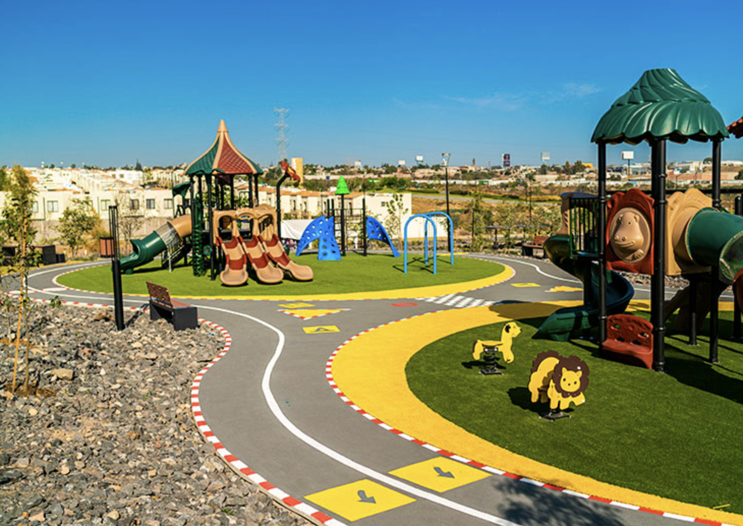 Colorful playground with slides and climbing structures set in a spacious, sunny outdoor park.
