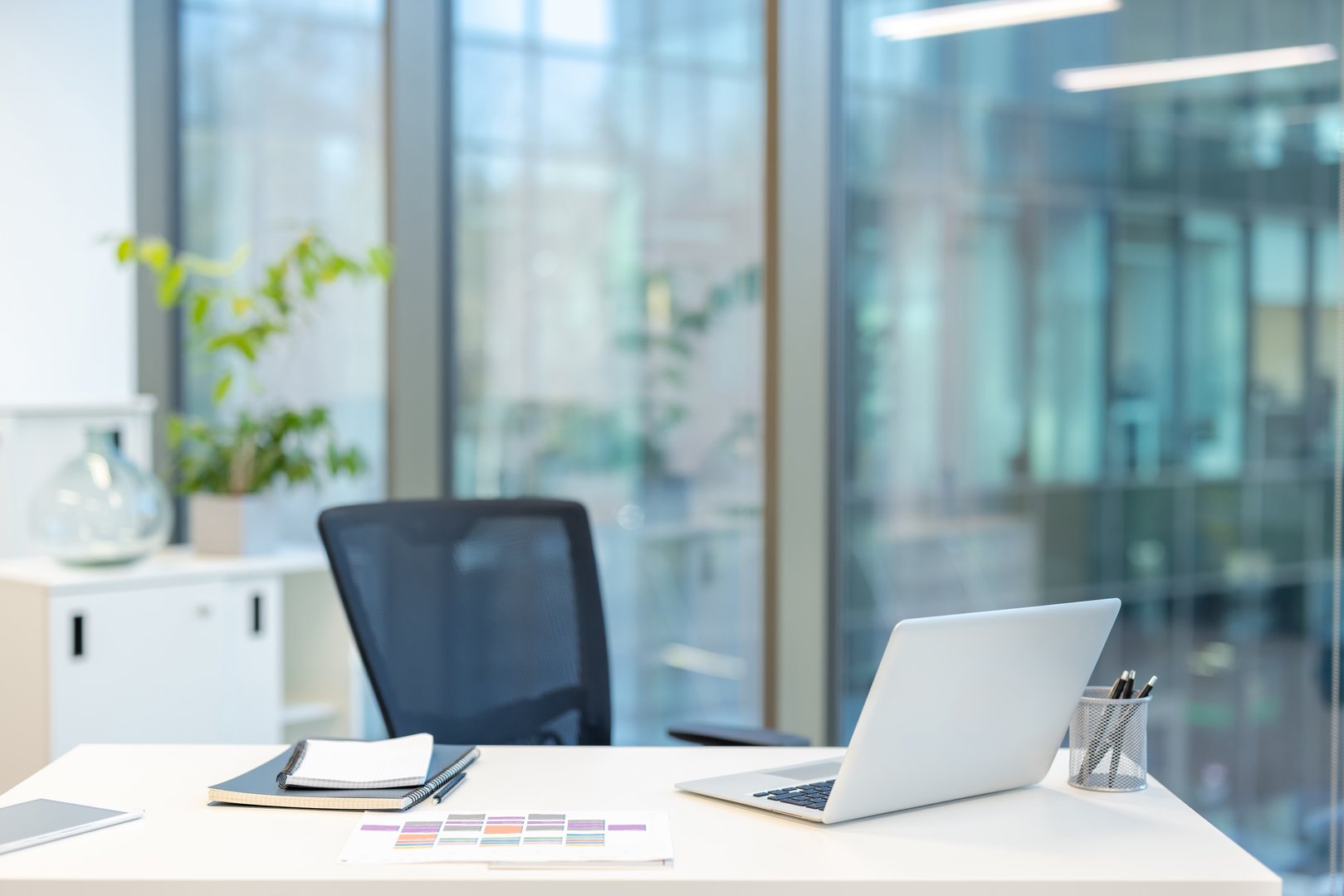 Corporate office workstation providing a professional and quiet environment for working, featuring a modern laptop and stationery on a clean desk, ready for business