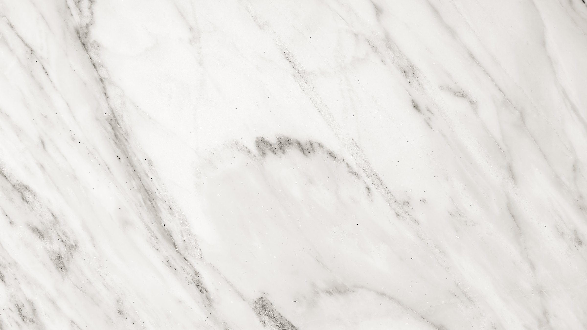 A close-up view of a white marble surface showcasing delicate grey veins and a smooth, polished finish, perfect for backgrounds