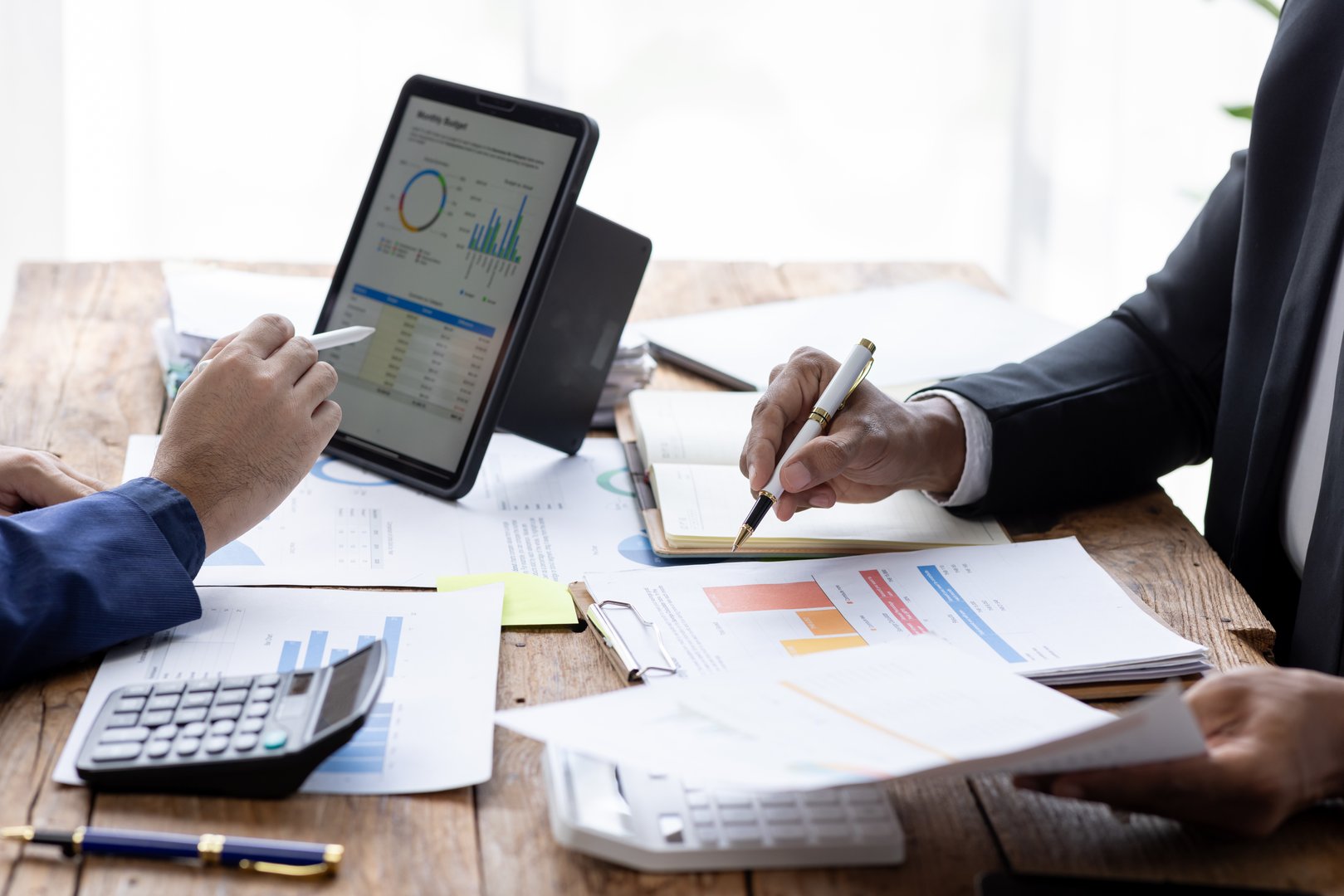 Group of confident business people point to graphs and charts to analyze market data, balance sheet, account, net profit to plan new sales strategies to increase production capacity.