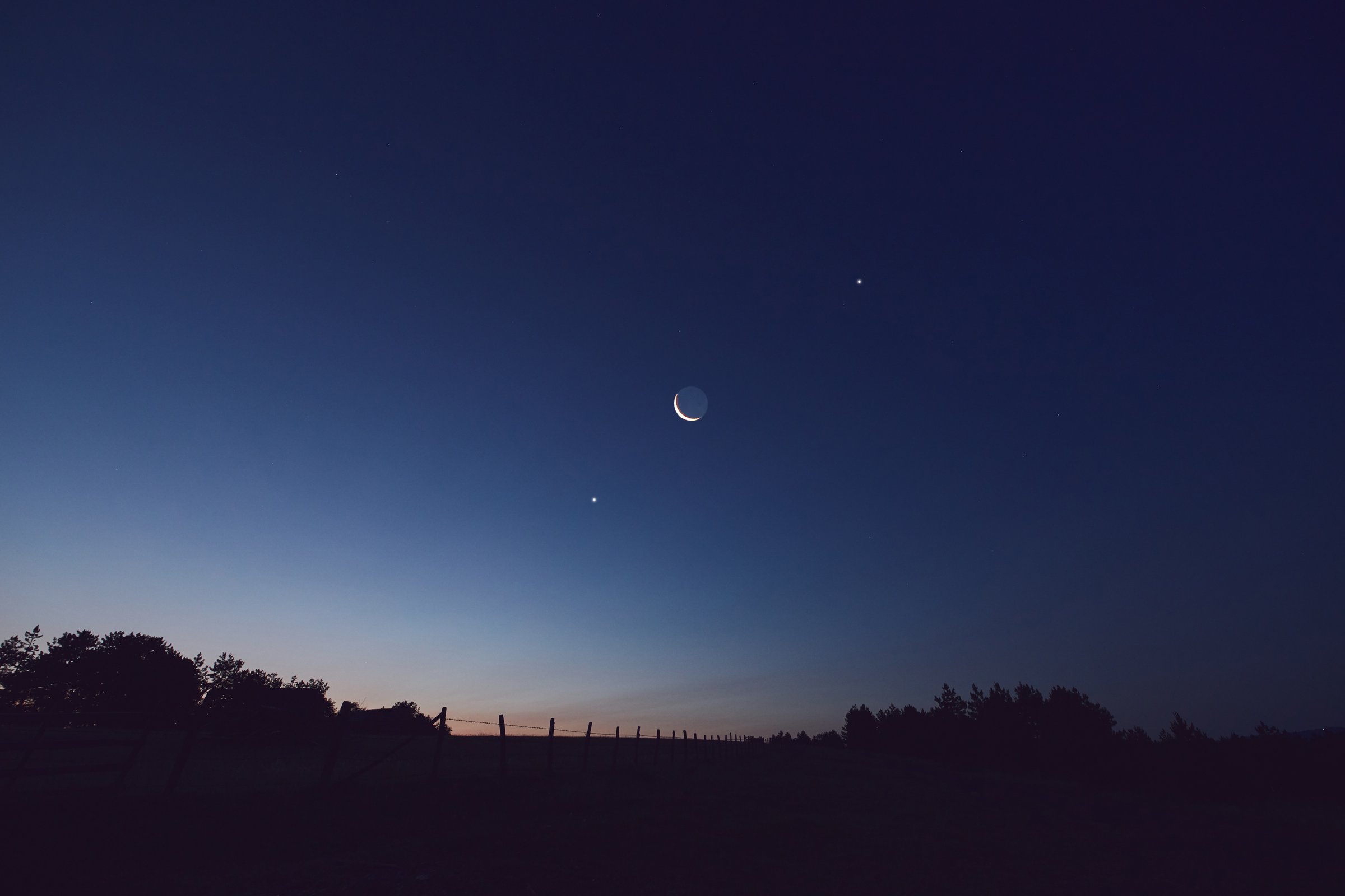 Morning old Moon with stars, planets and rural countryside tree silhouettes.
