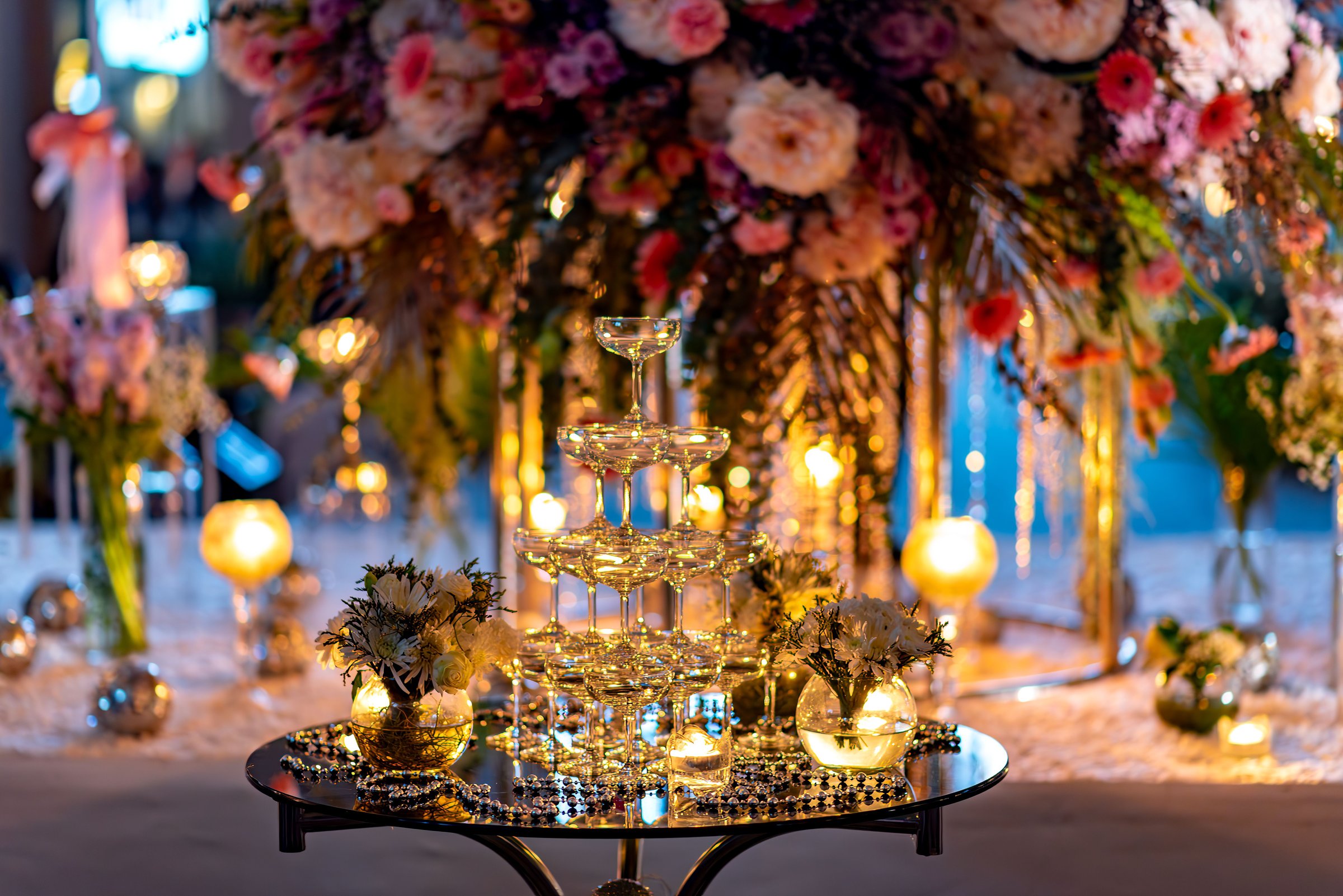 A Elegant wedding table setup with champagne tower, flowers, and warm lighting creating a romantic atmosphere.