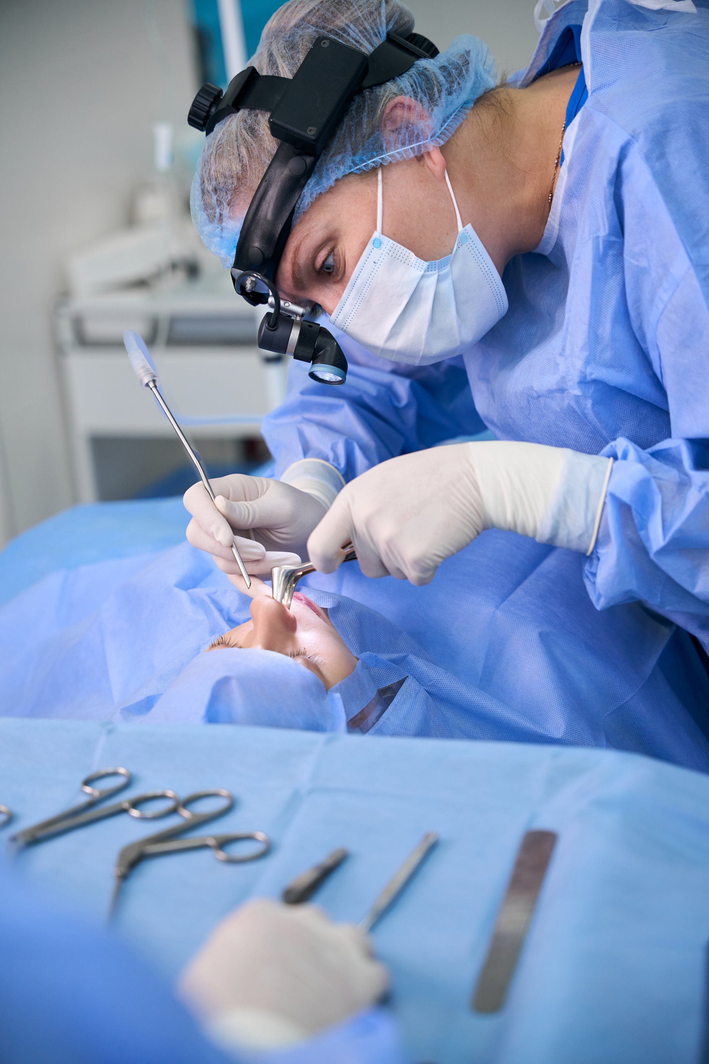 Female otolaryngologist surgeon performs a maxillary antrotomy in a modern clinic, using special instruments made of medical steel