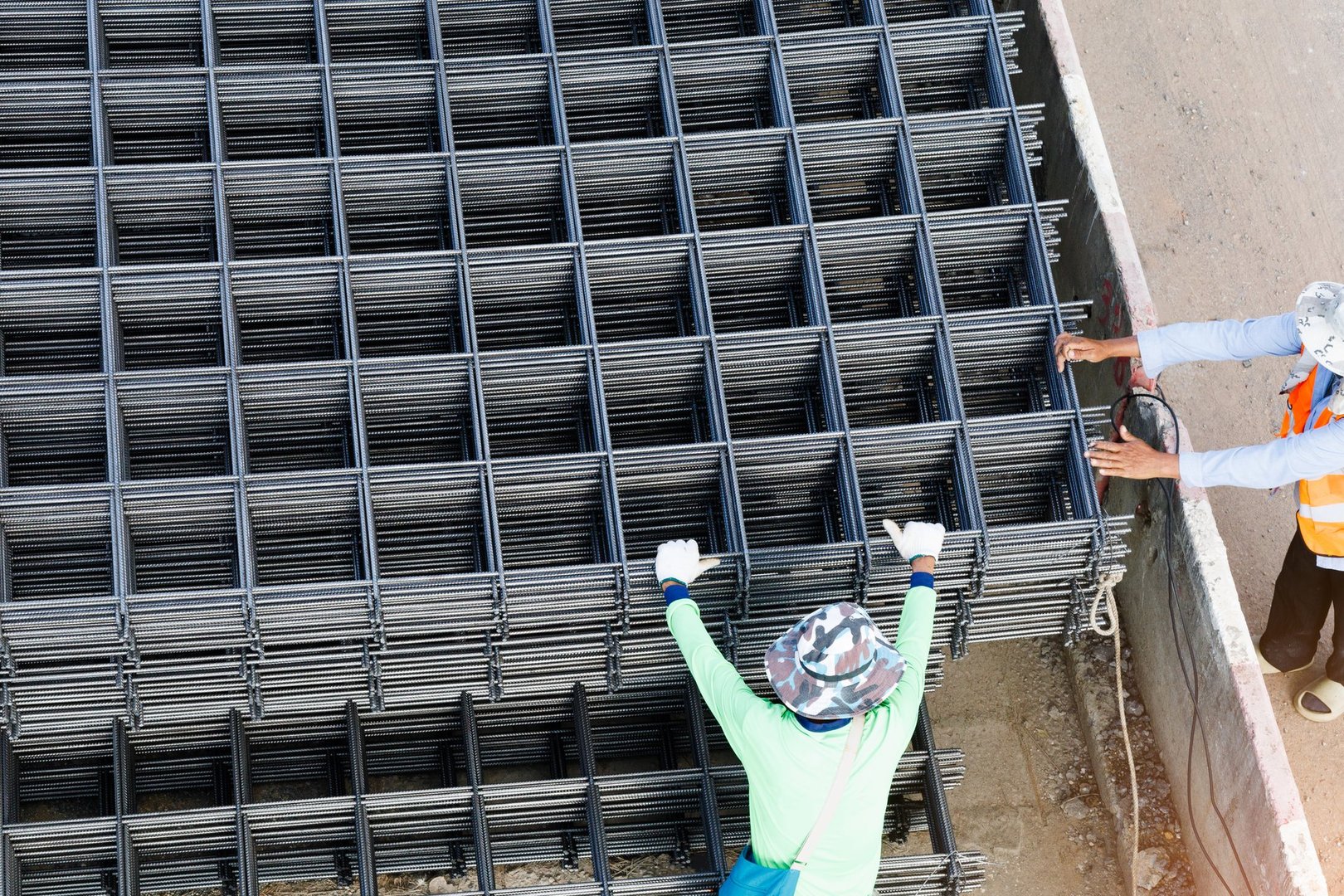 Crane lifting steel rebar mesh from truck