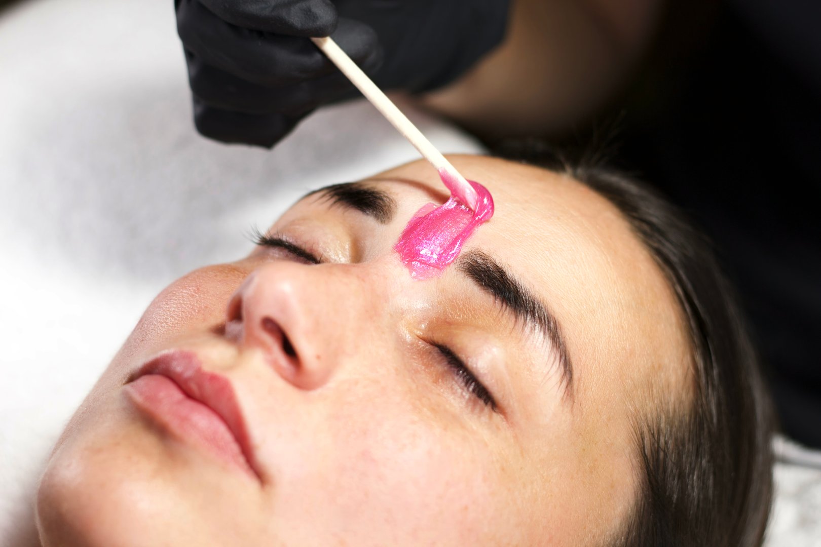 Beauty professional applying wax to eyebrows